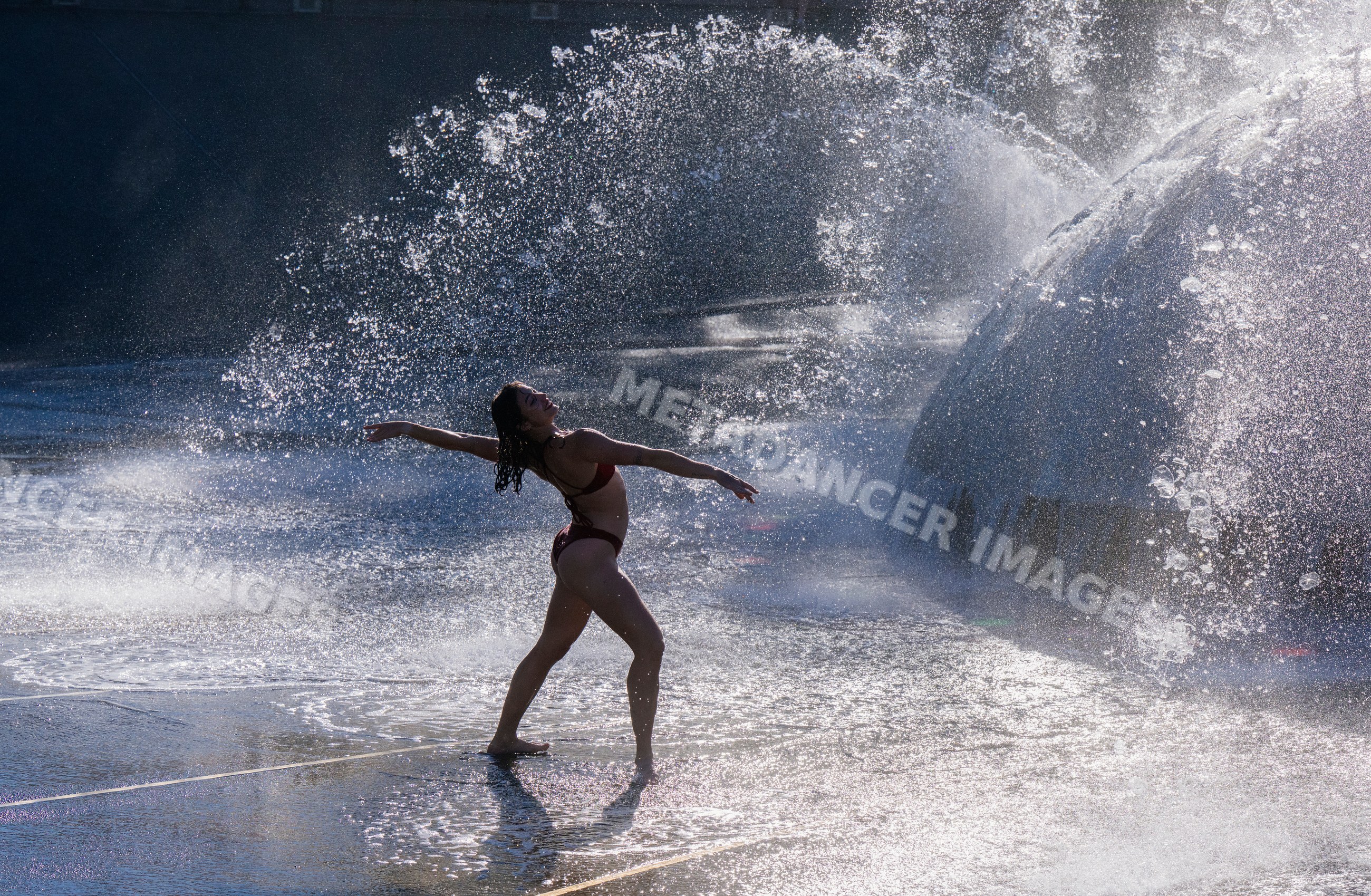 White woman dancing in splashing water at outdoor fountain