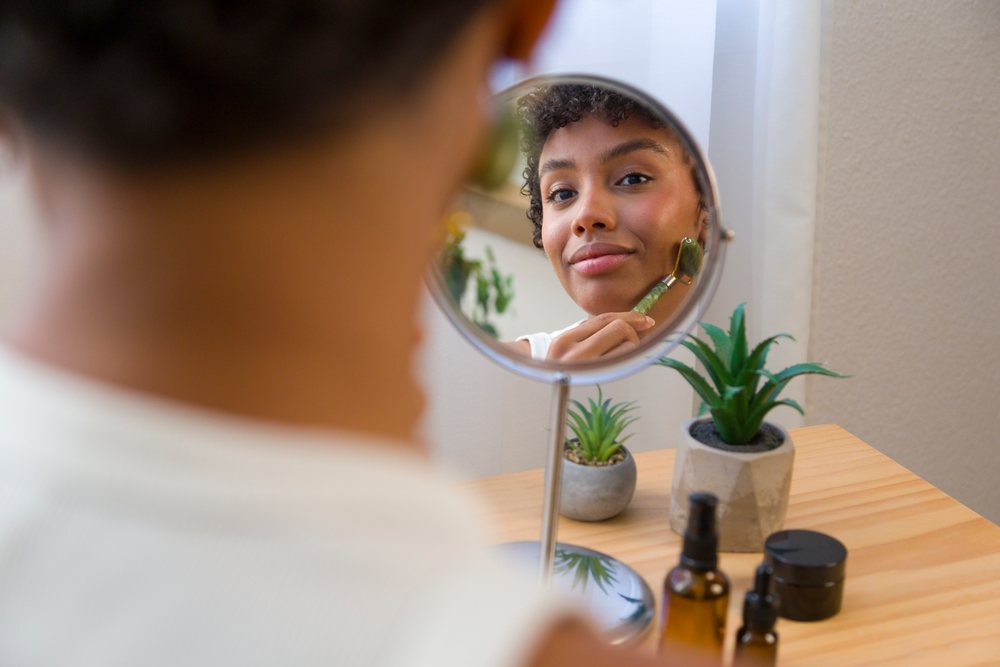 African American woman using jade facial roller