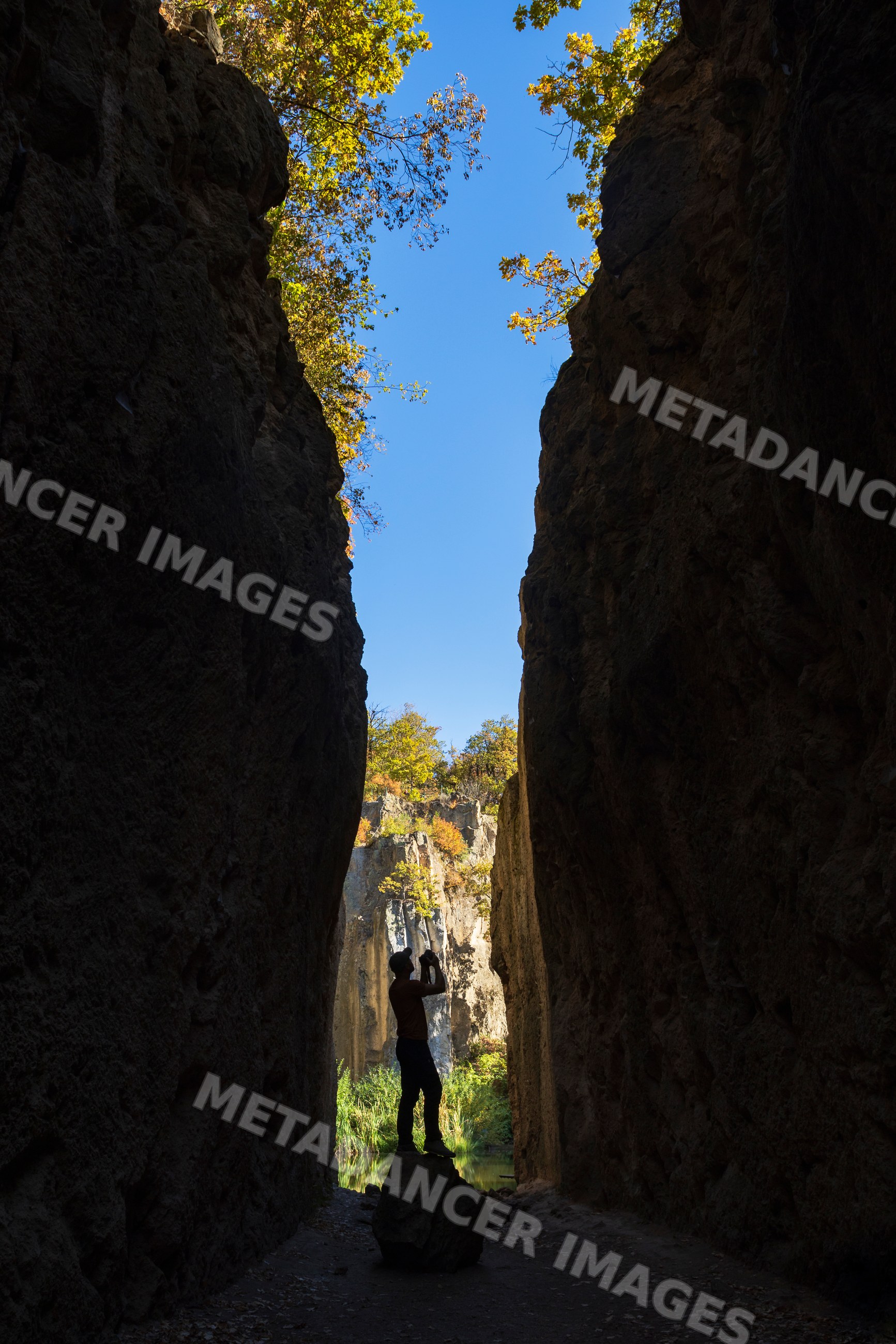 Photographer taking pictures in a narrow Abandoned Quarry at tarn