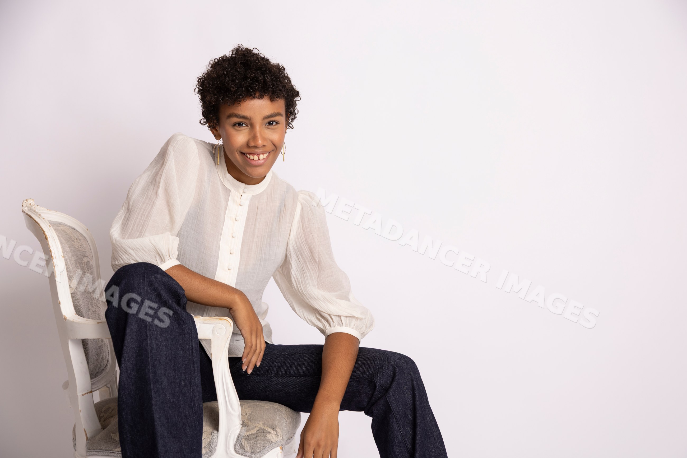 Young Hispanic woman sitting and smiling wearing white blouse