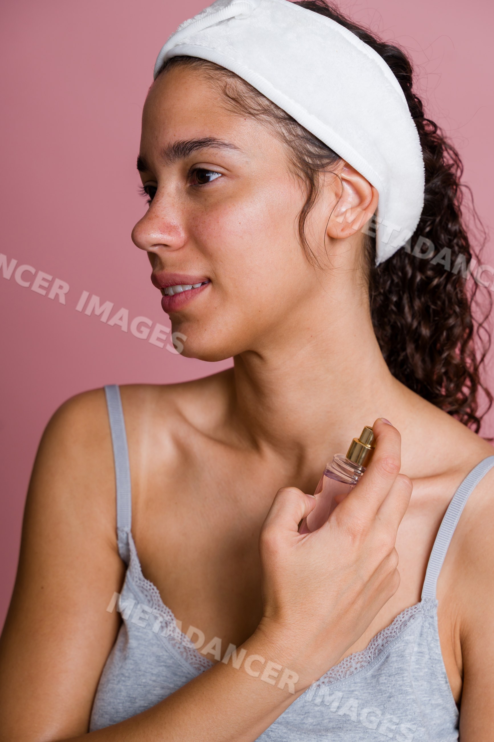 Hispanic woman applying facial spray in beauty shoot studio