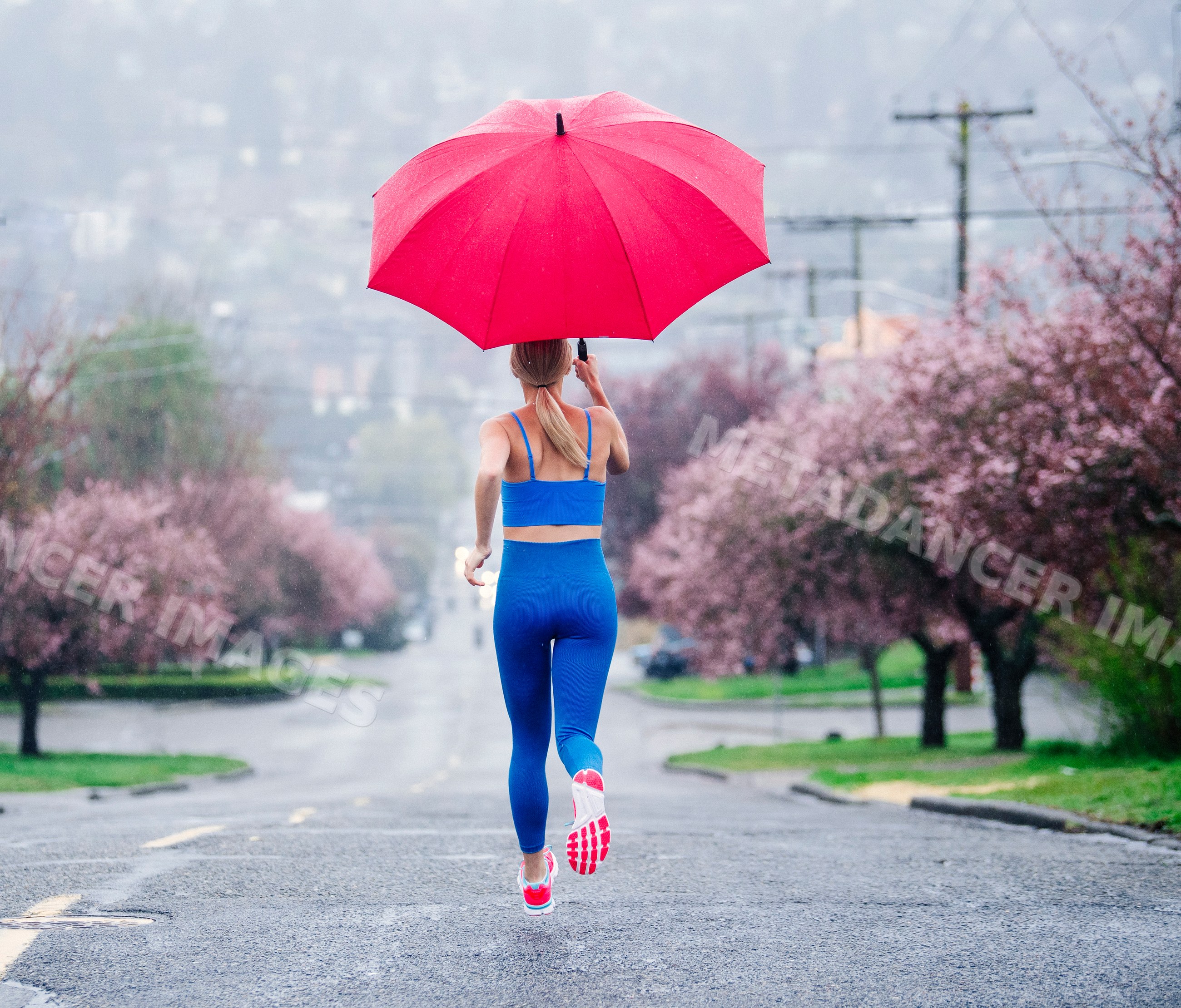 White woman running with a red umbrella on rainy street