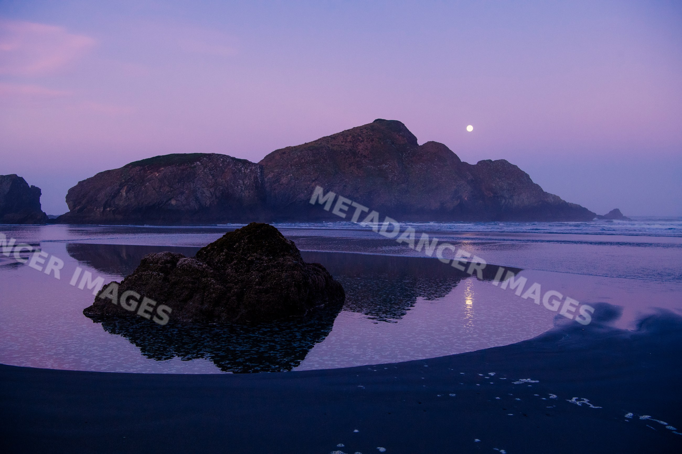 Rock formations and full moon reflection on Oregon coast at twilight