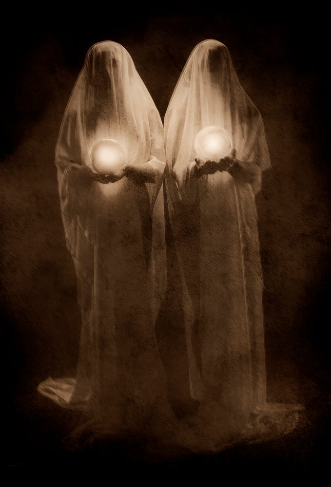 Two ghost figures holding glowing orbs against dark background