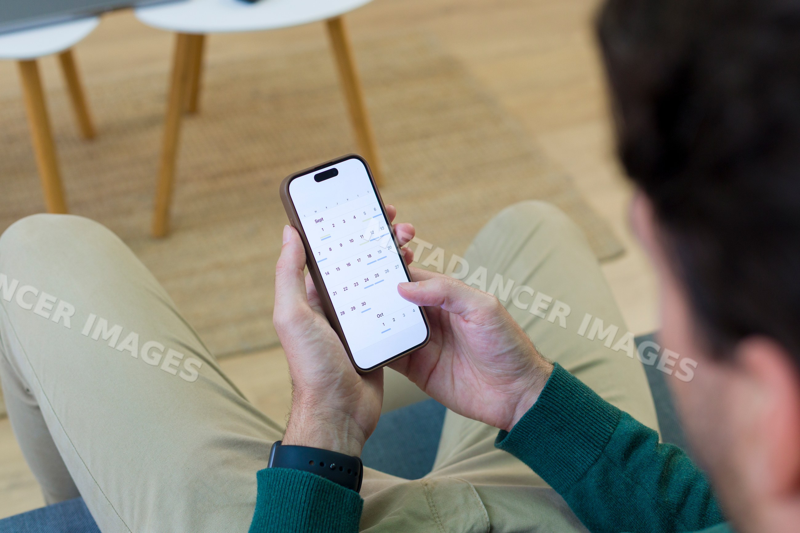 White person holding smartphone with calendar app indoors