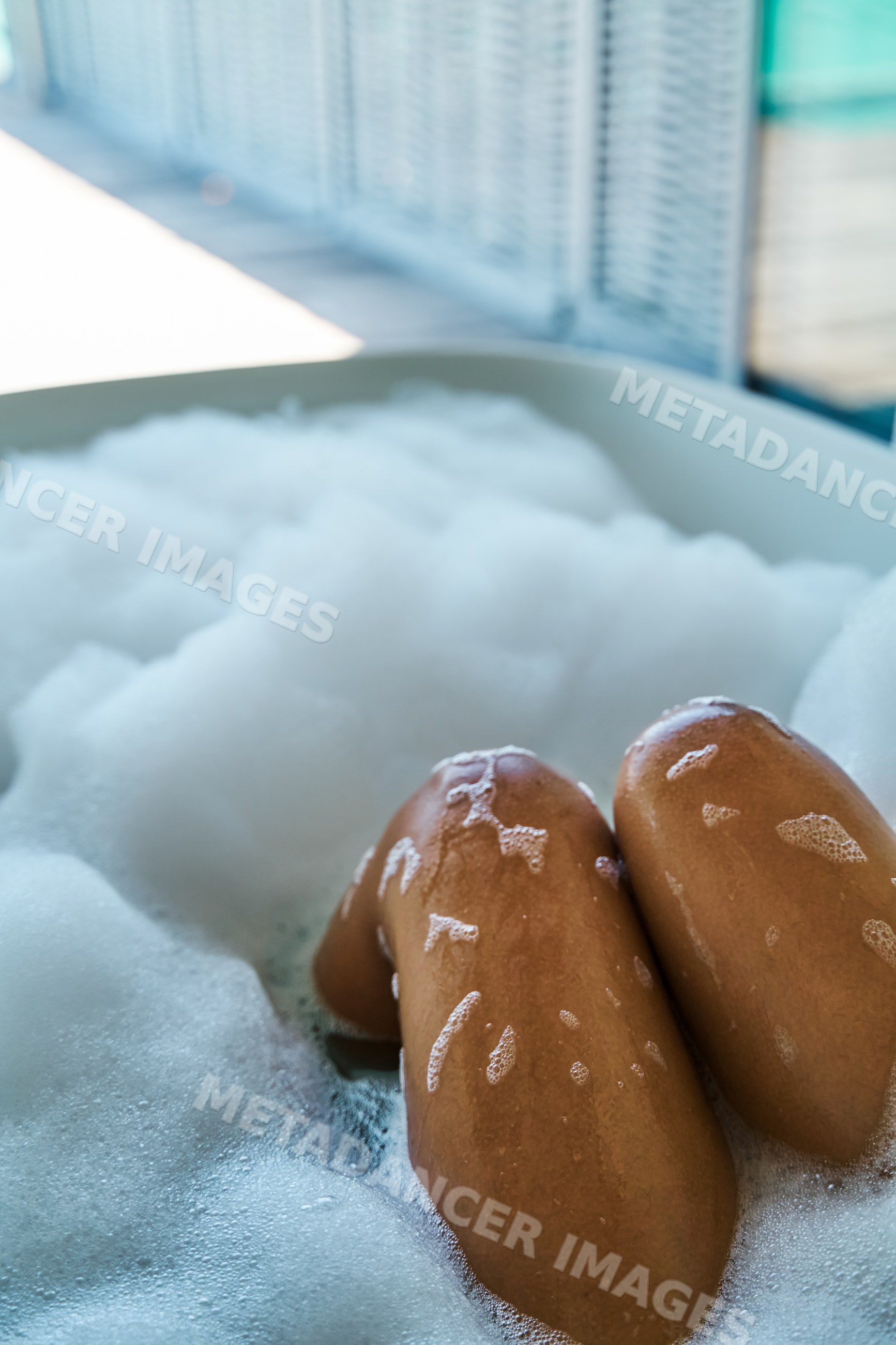Legs soaking in a bubble bathtub filled with foam