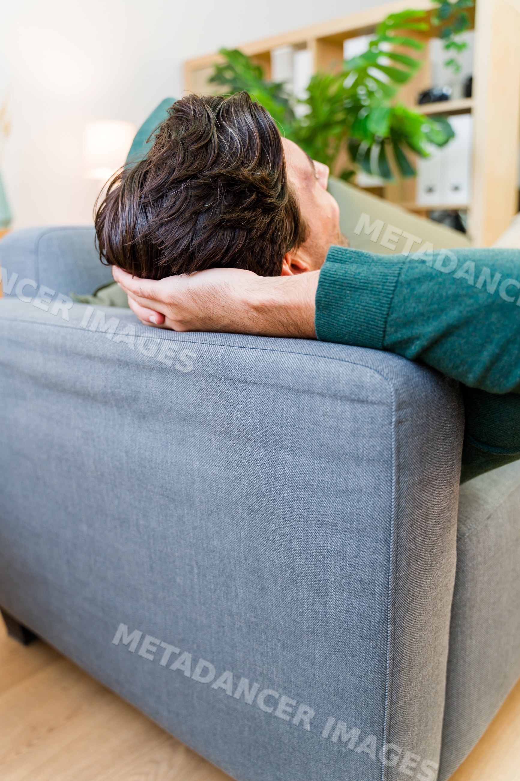 White man relaxing on grey sofa in modern living room