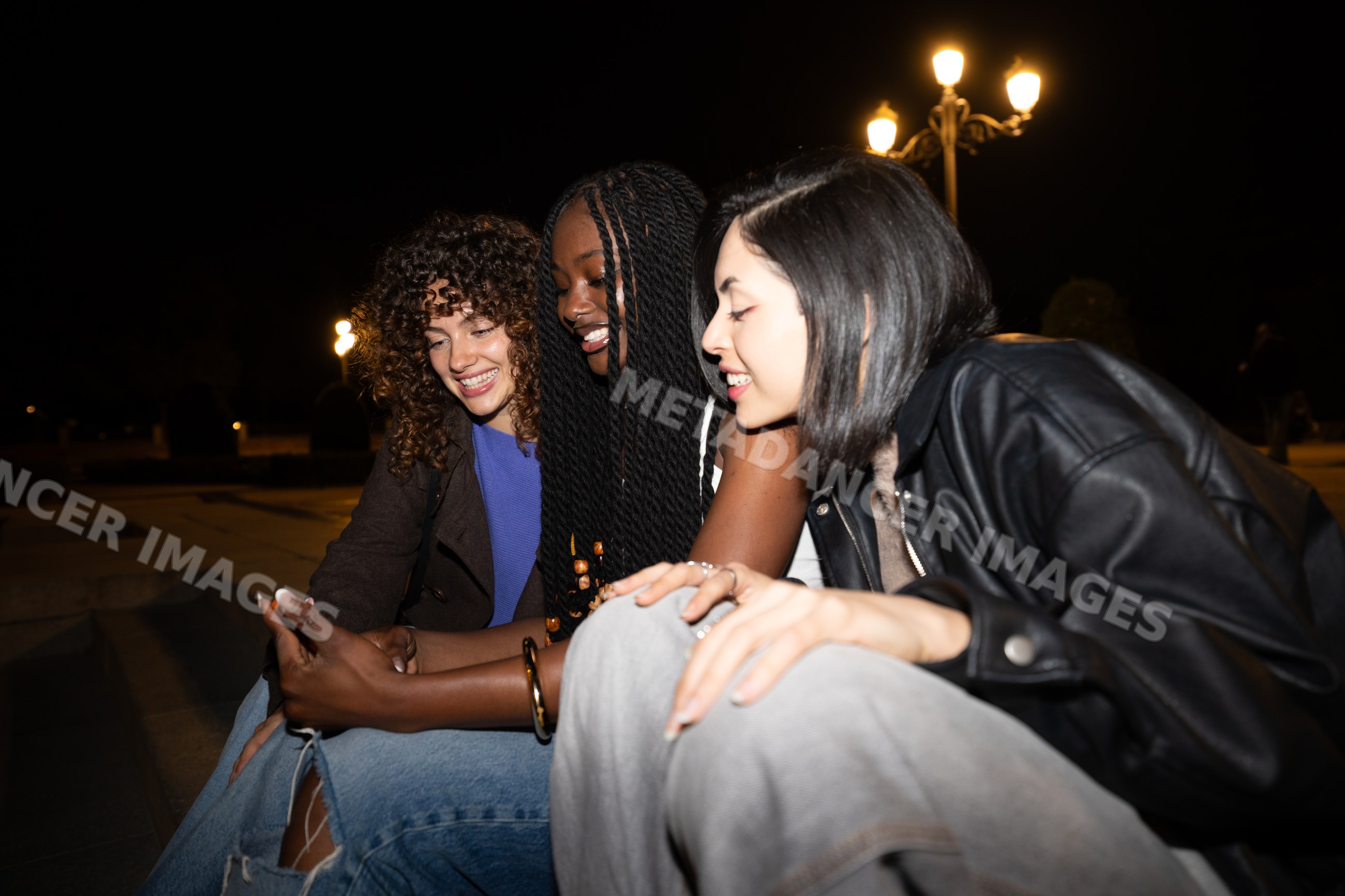 Three Hispanic, white and Black women sitting outdoors