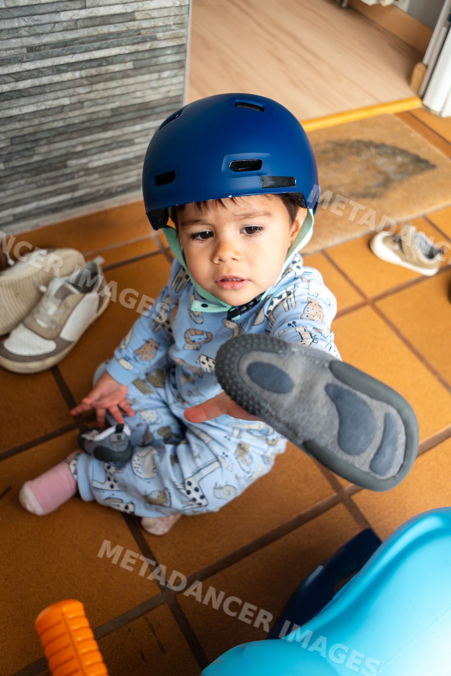 Toddler wearing helmet holding shoe sitting featuring a white model
