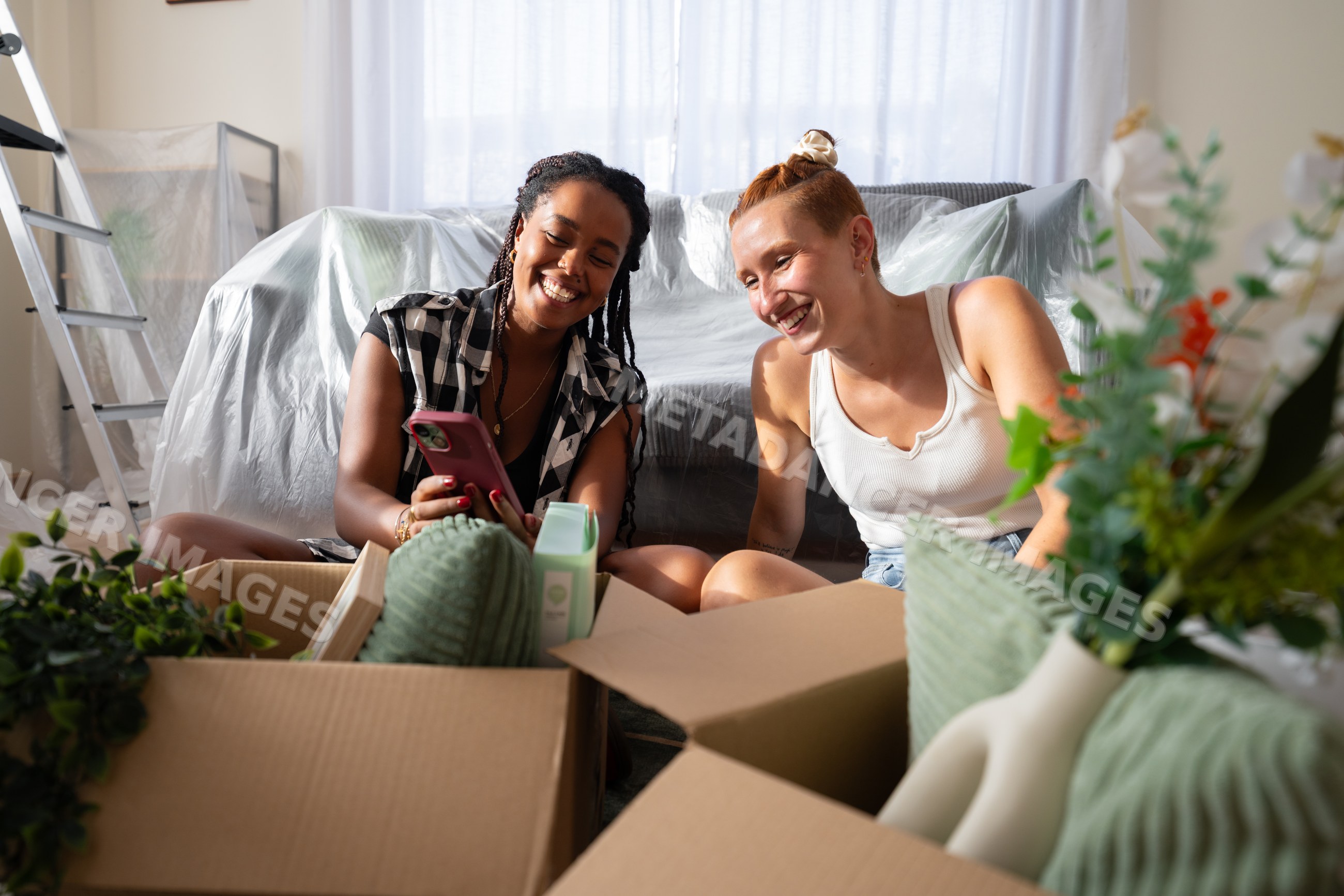 Two African American and white women unpack and enjoy decorating their