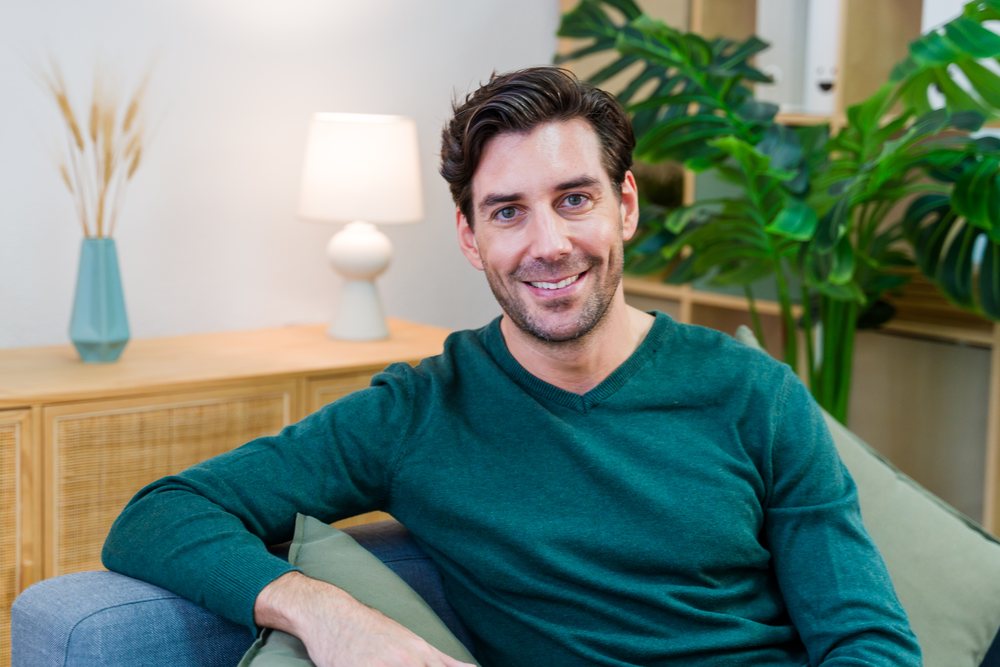 Smiling white man sitting on couch in modern living room interior