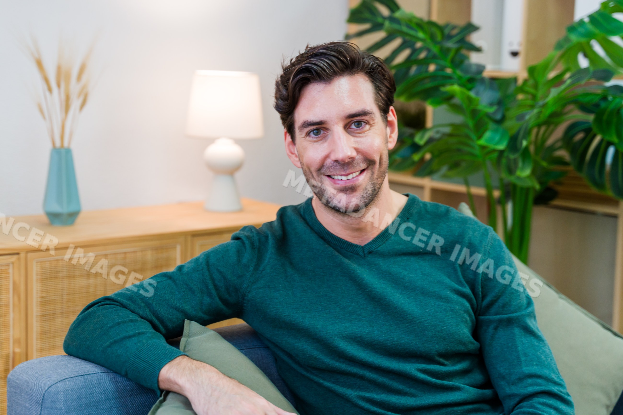 Smiling white man sitting on couch in modern living room interior
