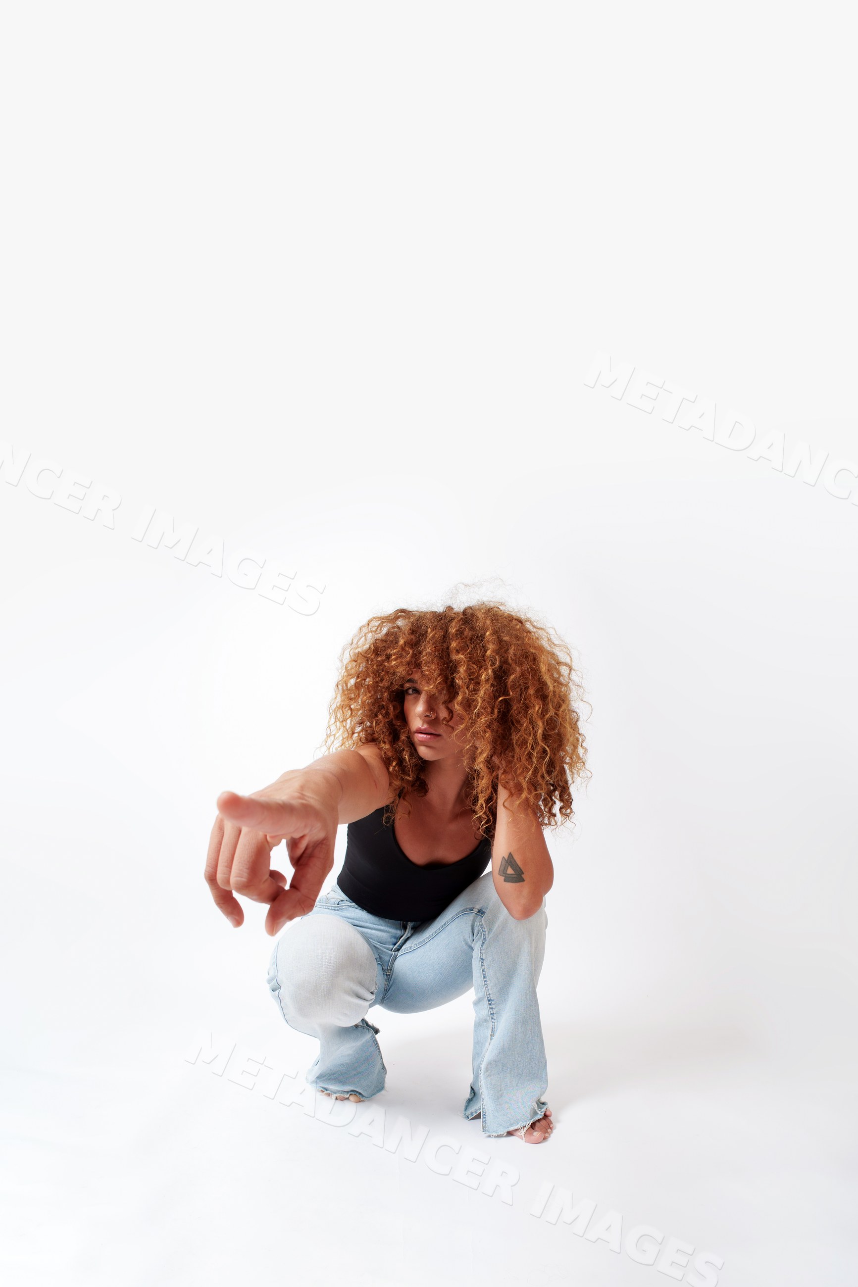 Hispanic woman with curly red hair crouching and pointing