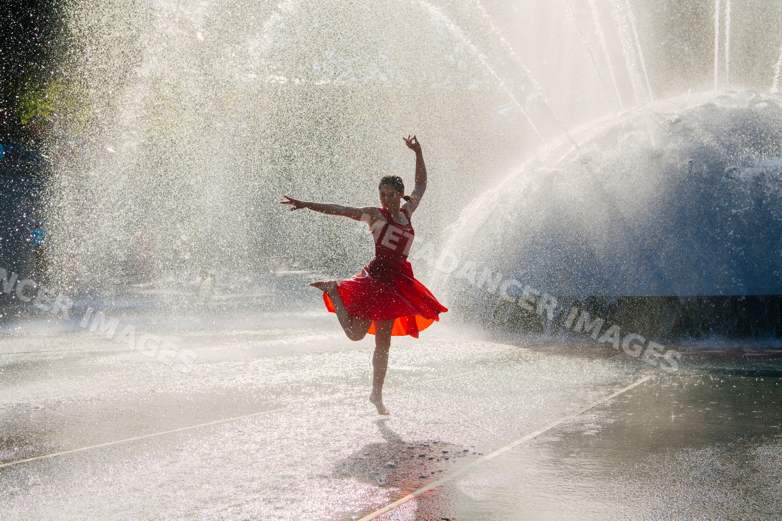 White woman dancing in water spray from fountain outdoors