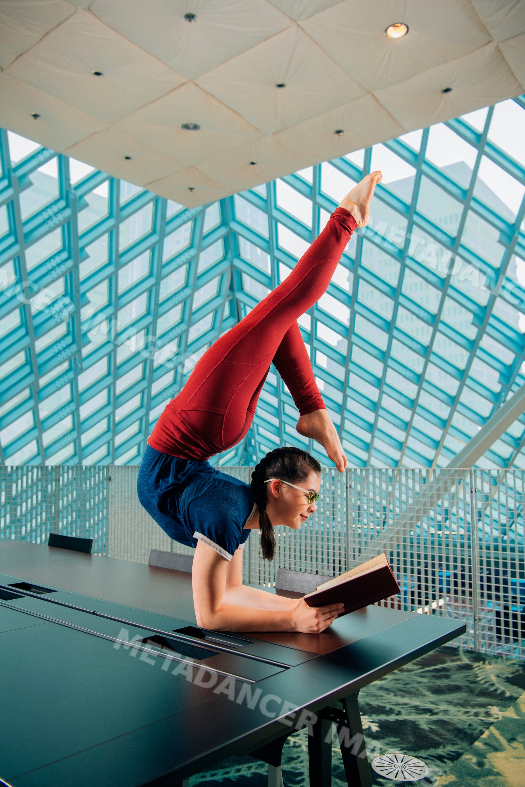 A woman reads a book while doing a handstand in a library
