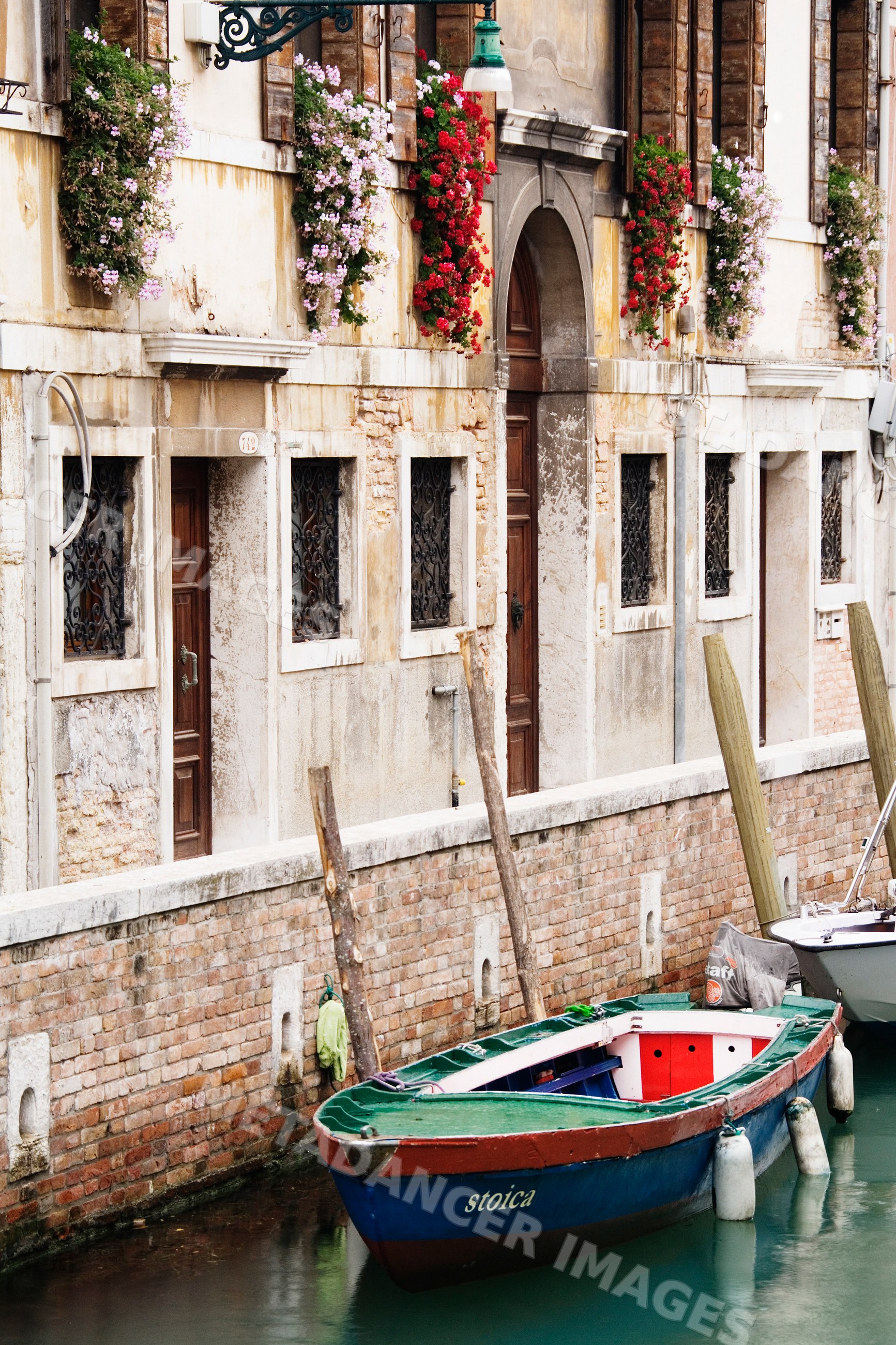 Rowboats moored along canal with flower-decorated historic building