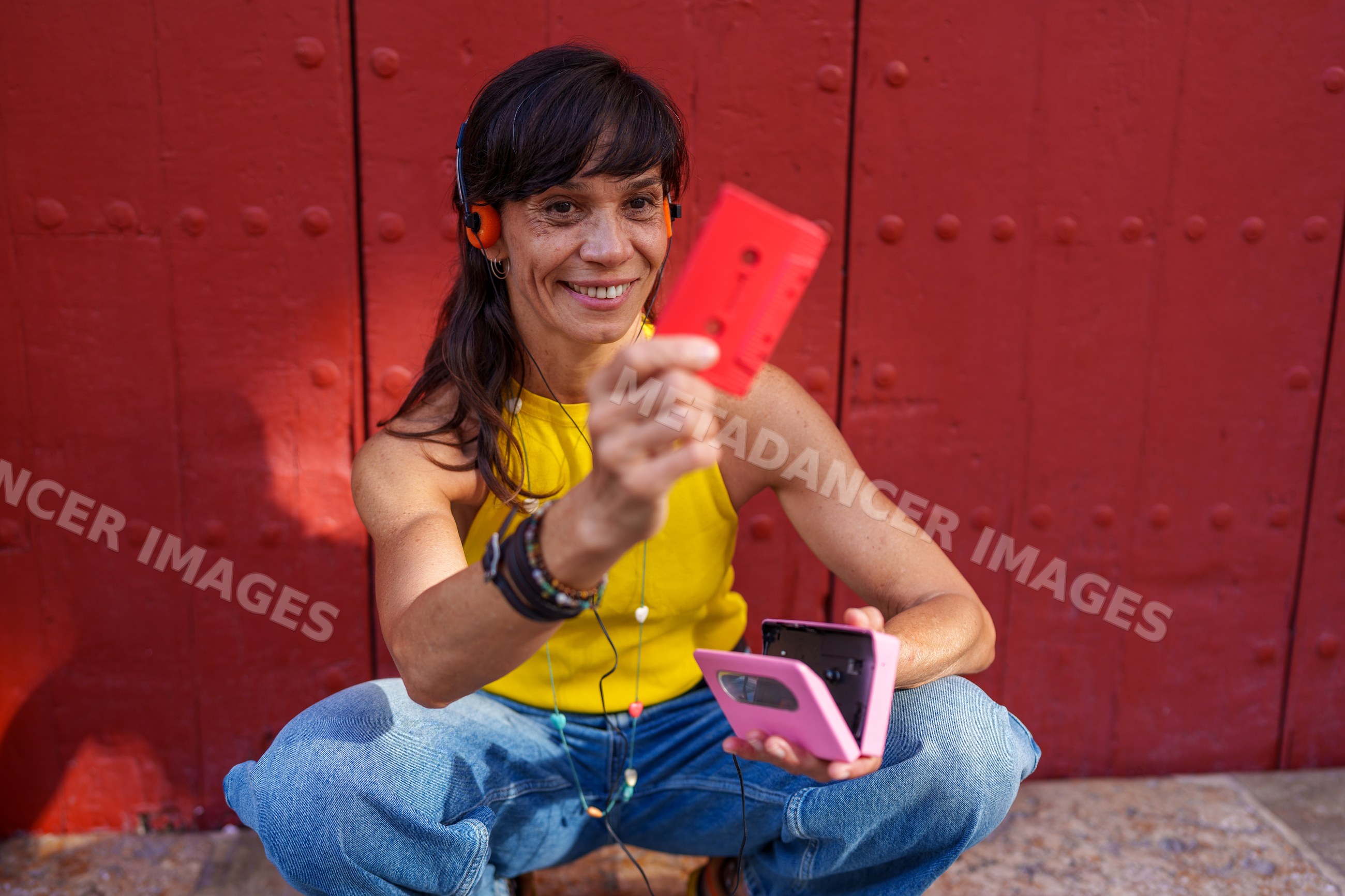 Hispanic woman enjoying retro cassette player and tape outdoors