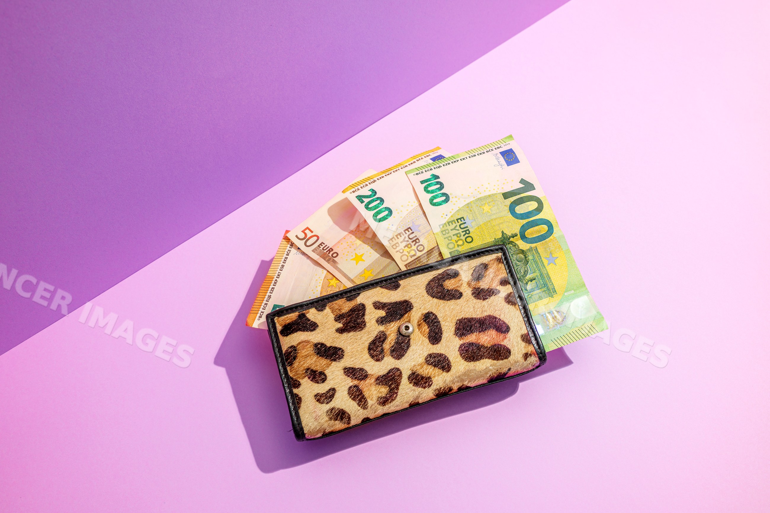Wallet with euro banknotes on purple studio background