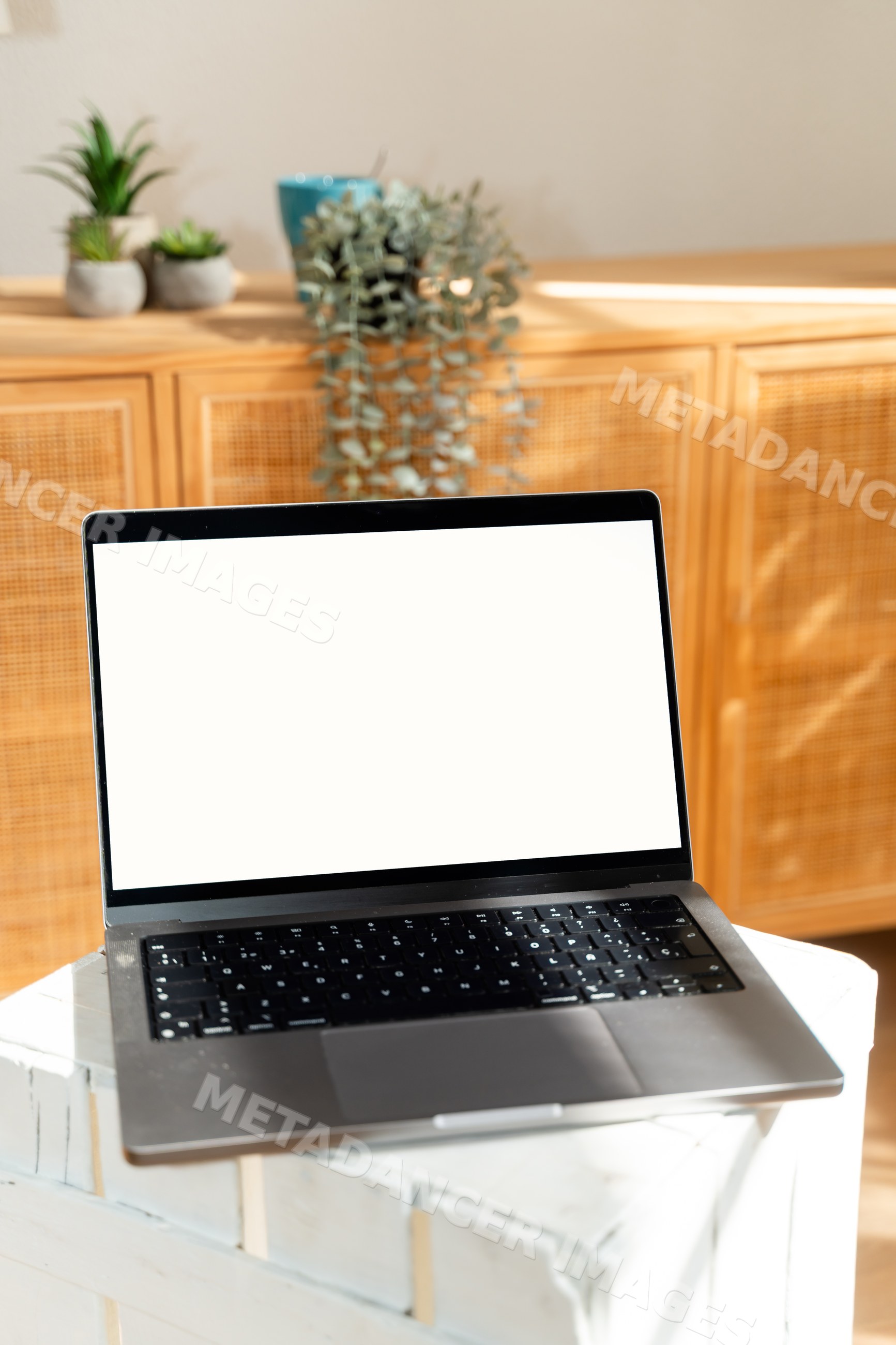 Laptop with blank screen on white crate indoors with wooden cabinet