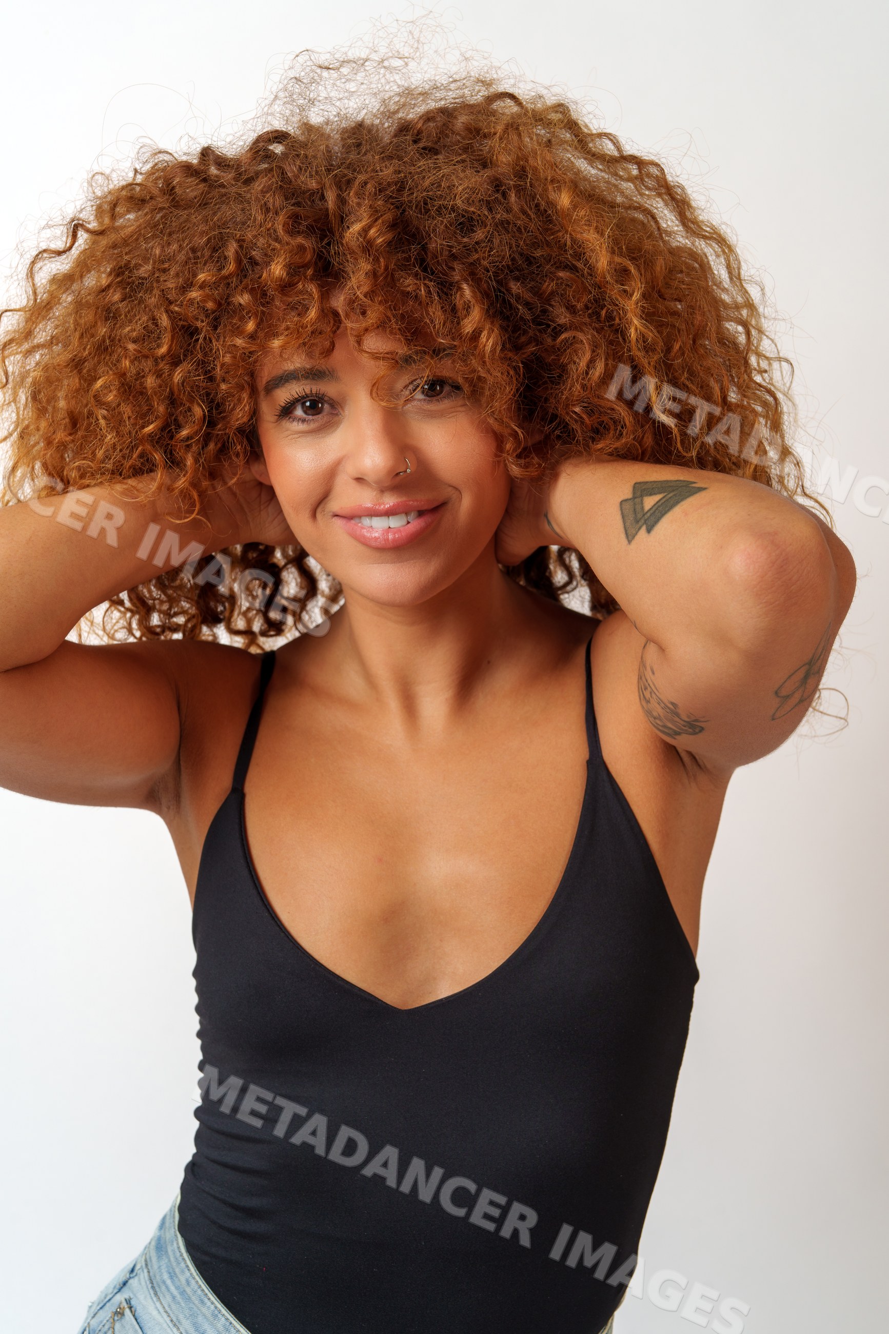 Hispanic woman with curly red hair and tattoos posing