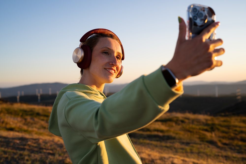Young white woman takes a selfie with headphones on outdoors