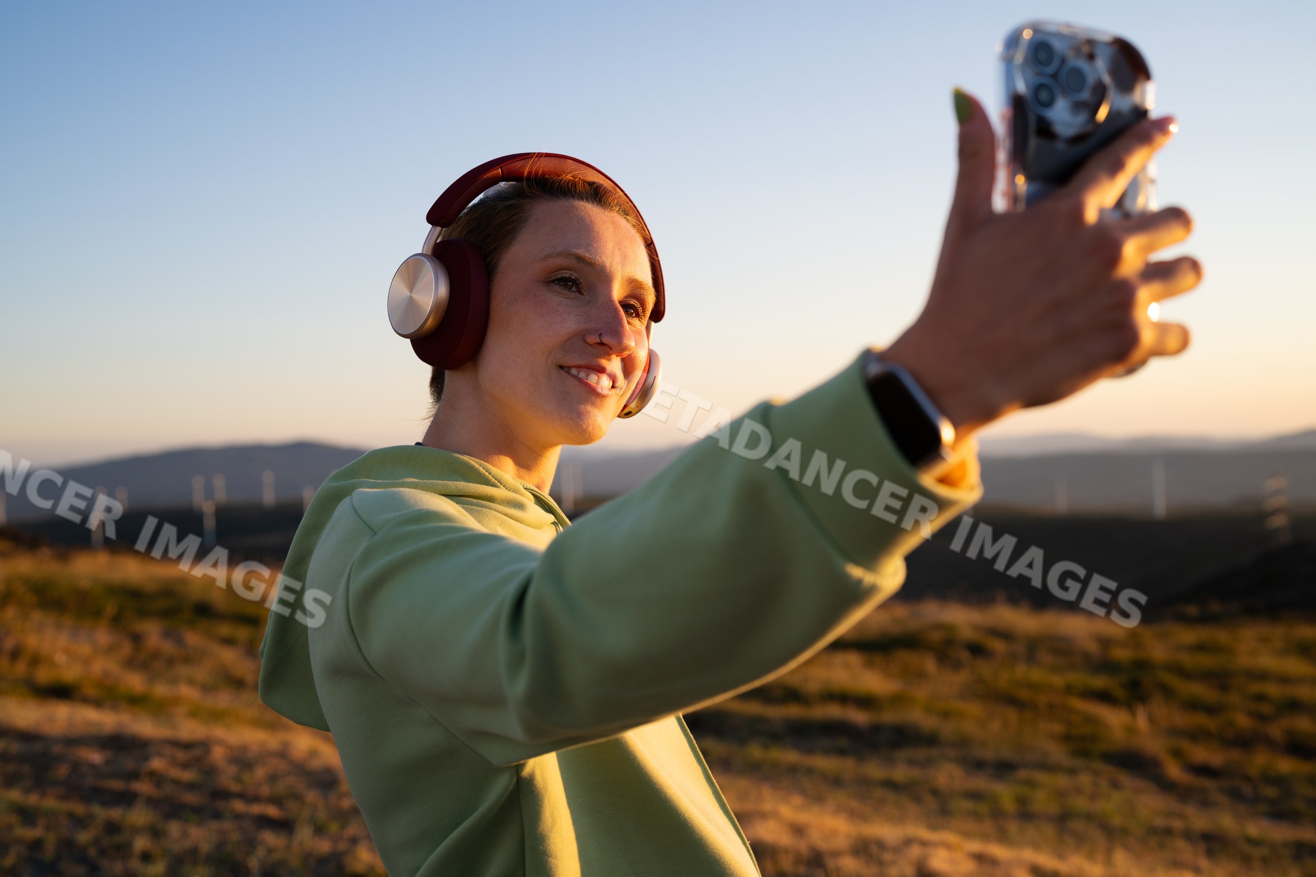 Young white woman takes a selfie with headphones on outdoors