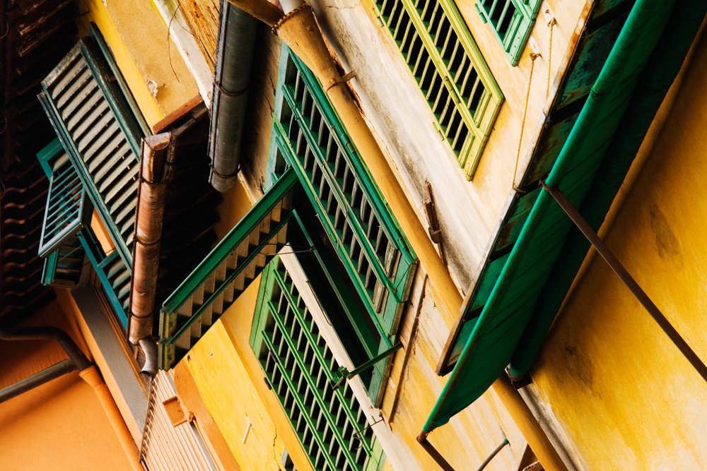 Green window shutters on historic yellow building, italy