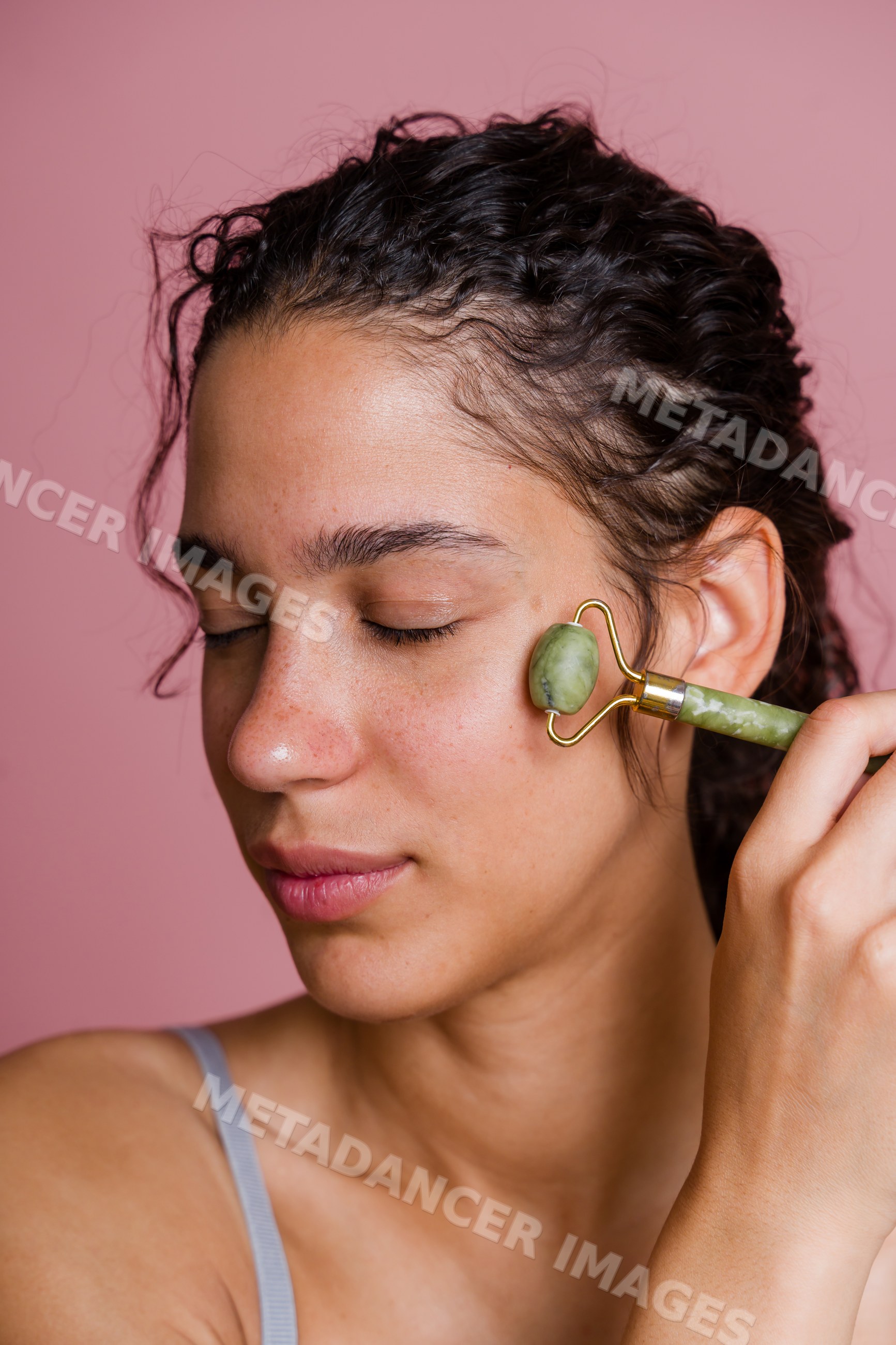 Hispanic woman using jade roller for facial massage