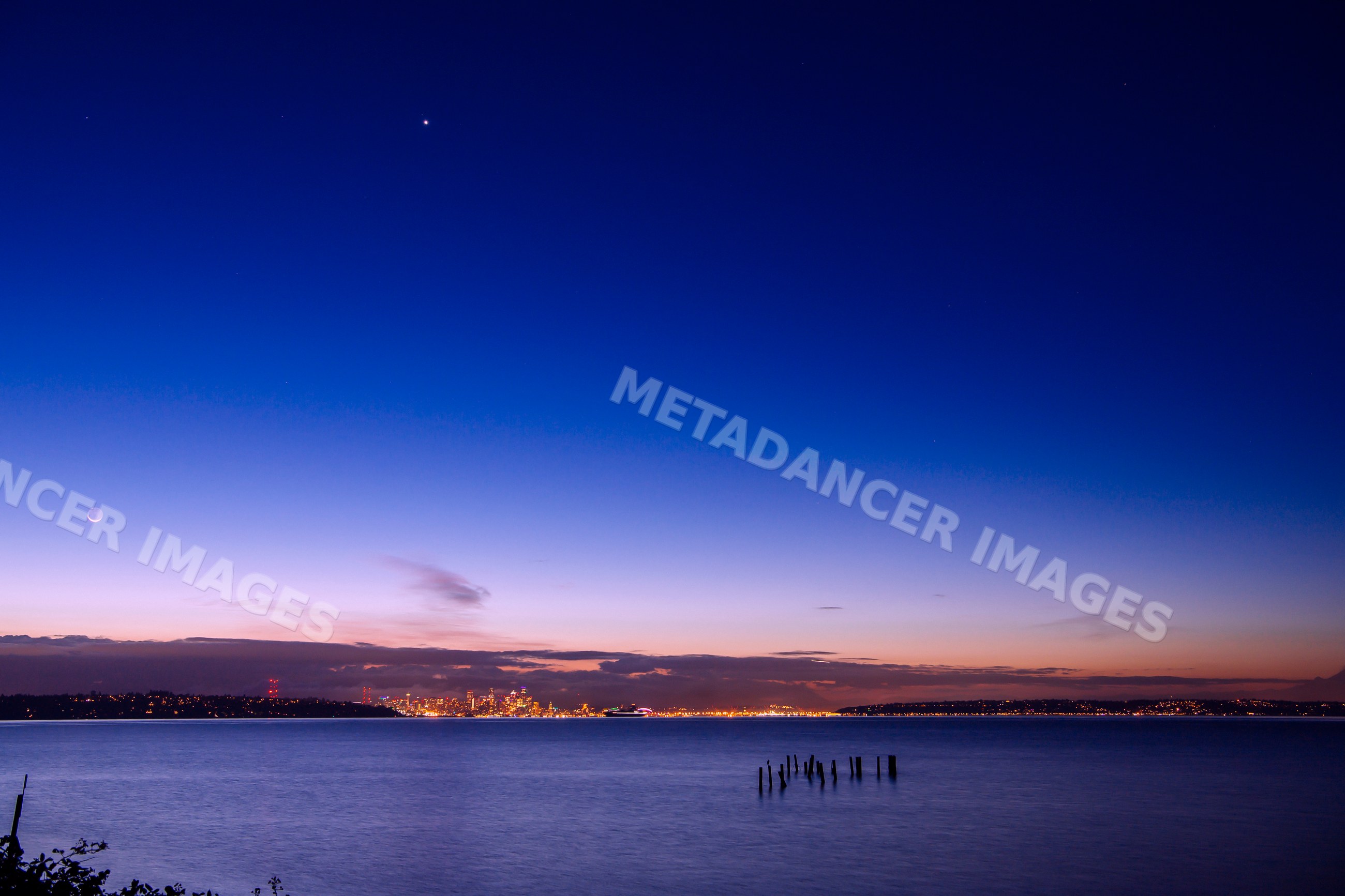 Seattle city skyline night scene over water with moon and stars