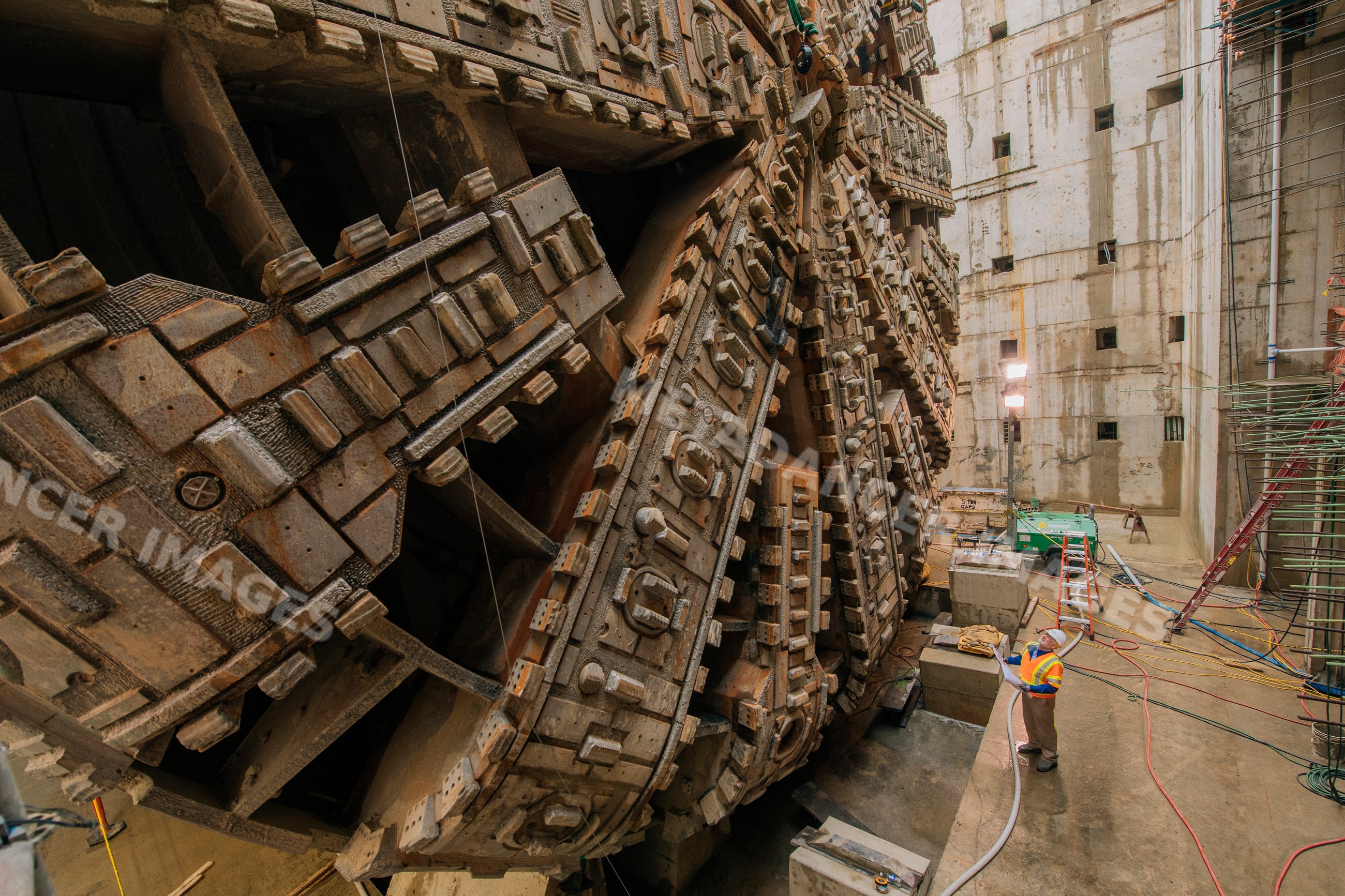 Two white workers inspect a huge tunnel boring machine