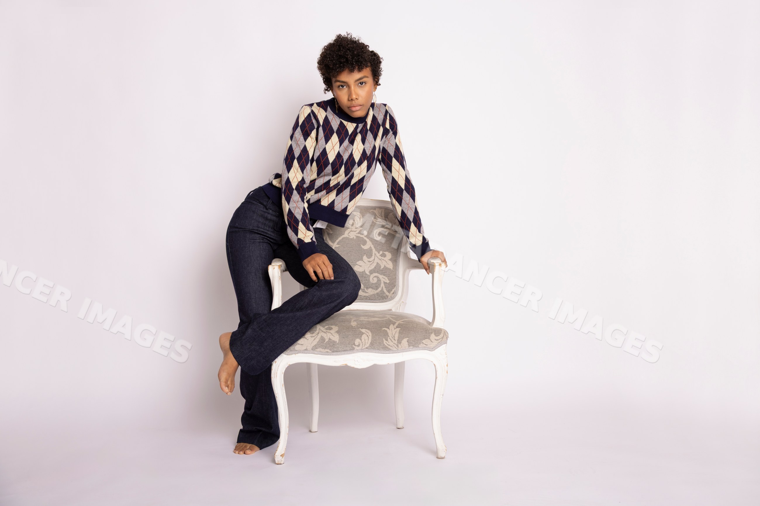 Young Hispanic woman posing with armchair in fashion studio