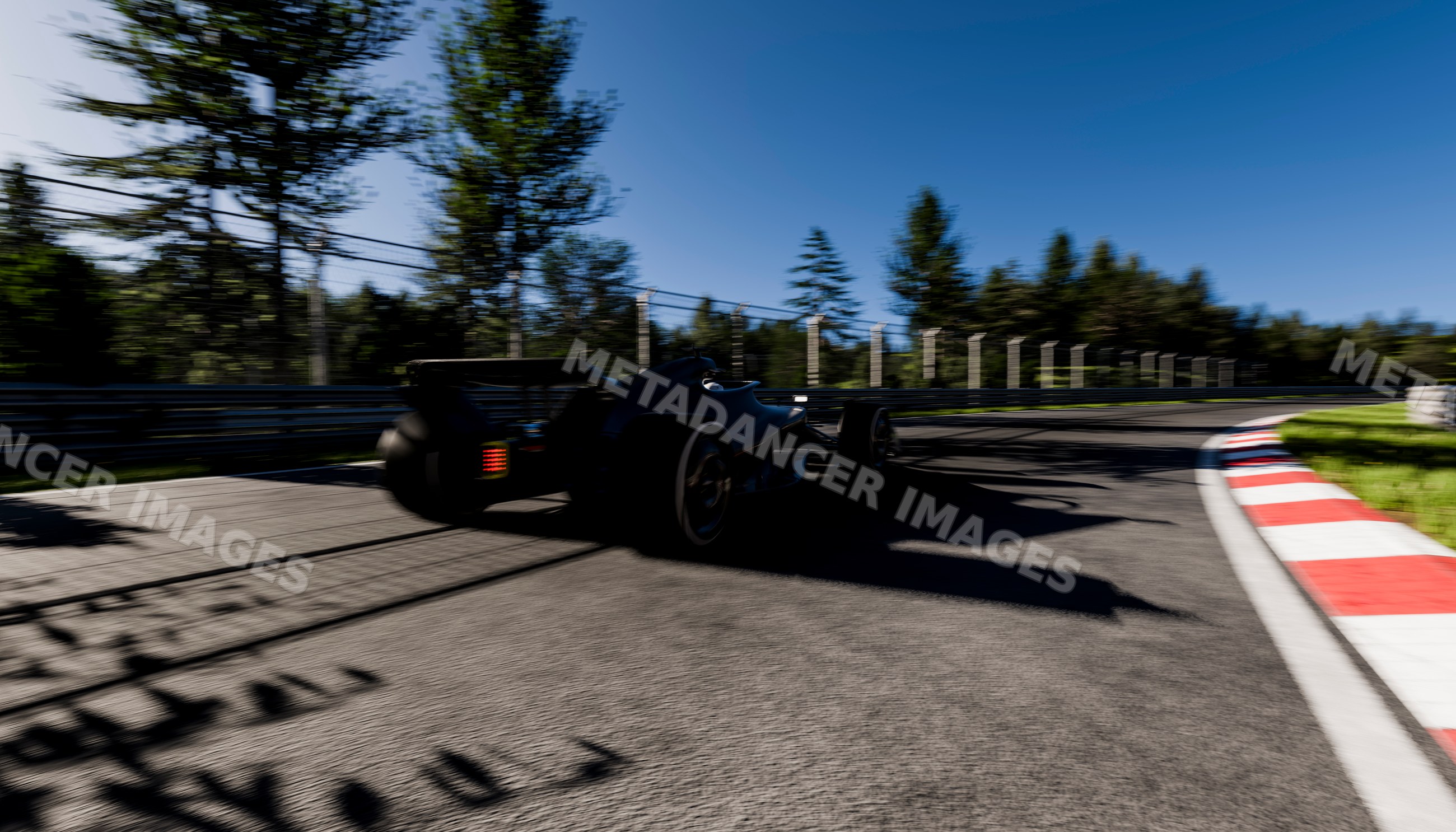 Black race car speeding around a curve on a racetrack