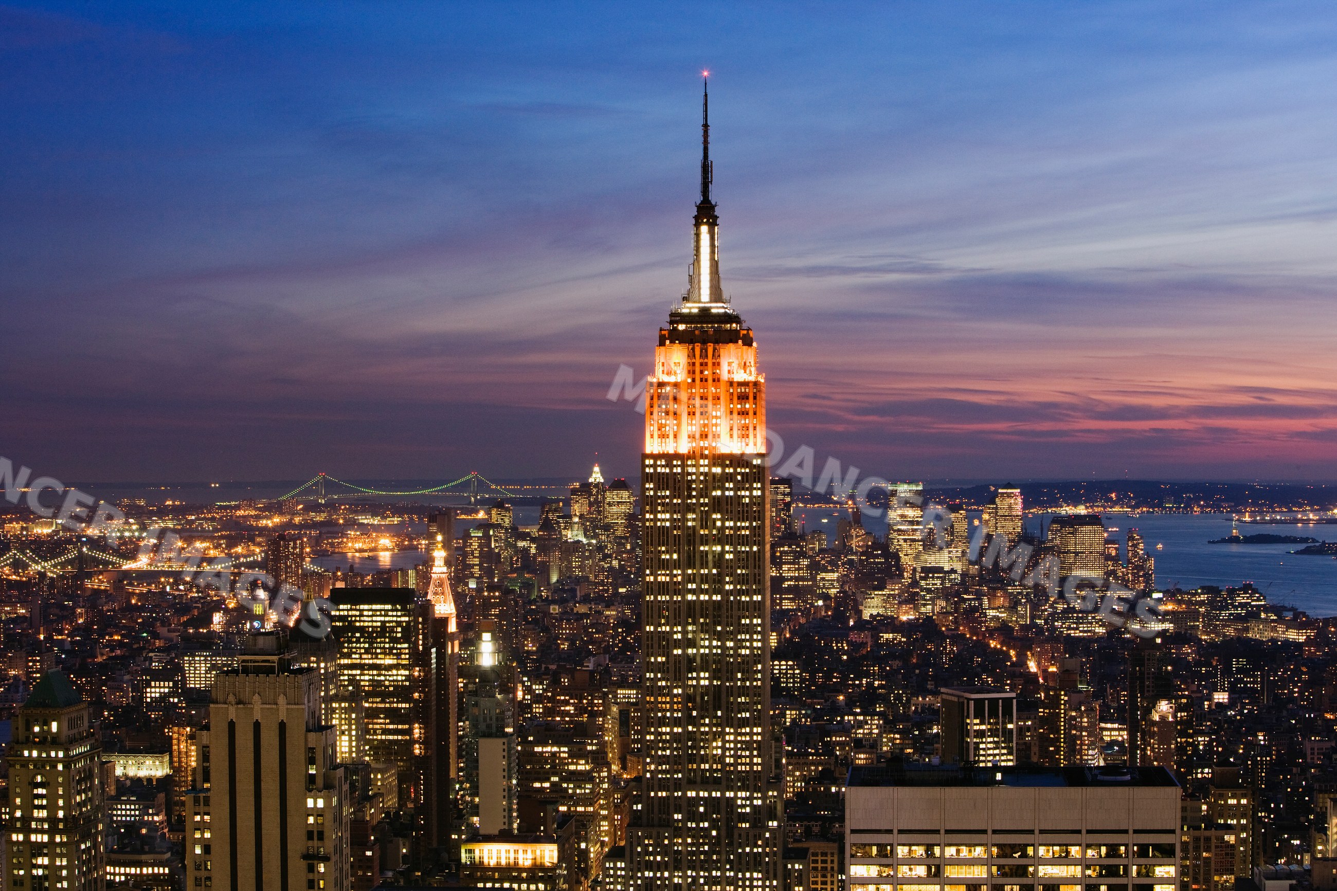 Empire state building illuminated with new york city skyline at dusk