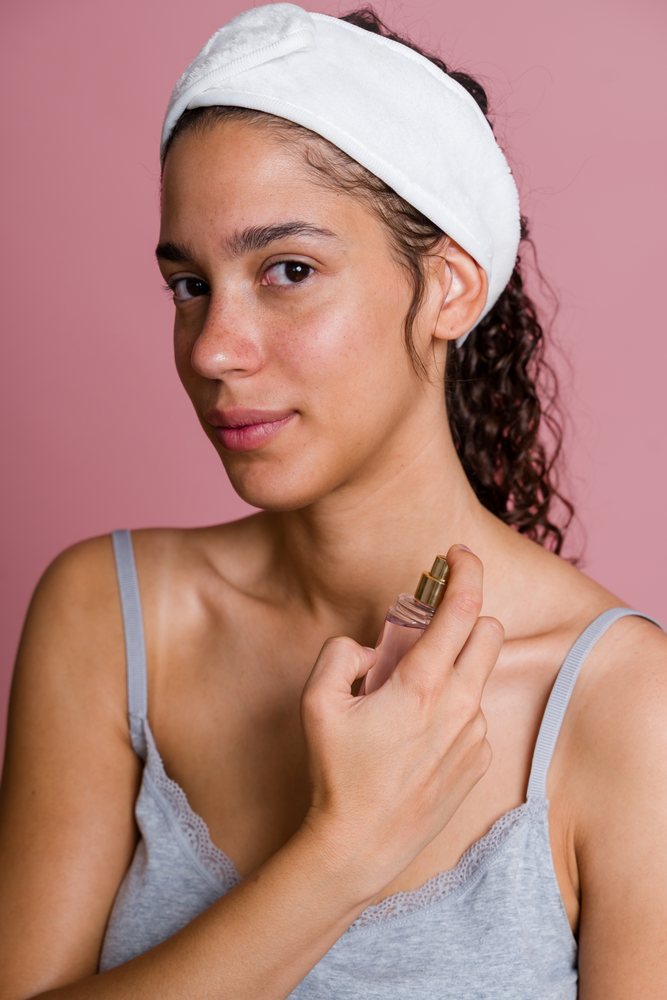 Hispanic woman applying facial mist in beauty shoot