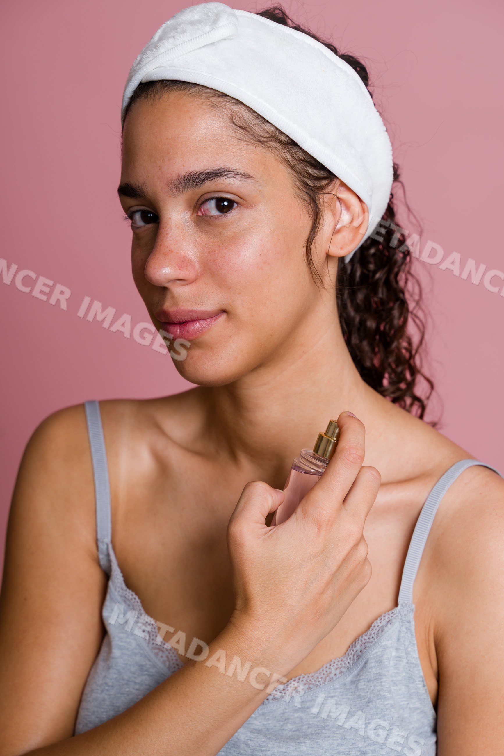 Hispanic woman applying facial mist in beauty shoot