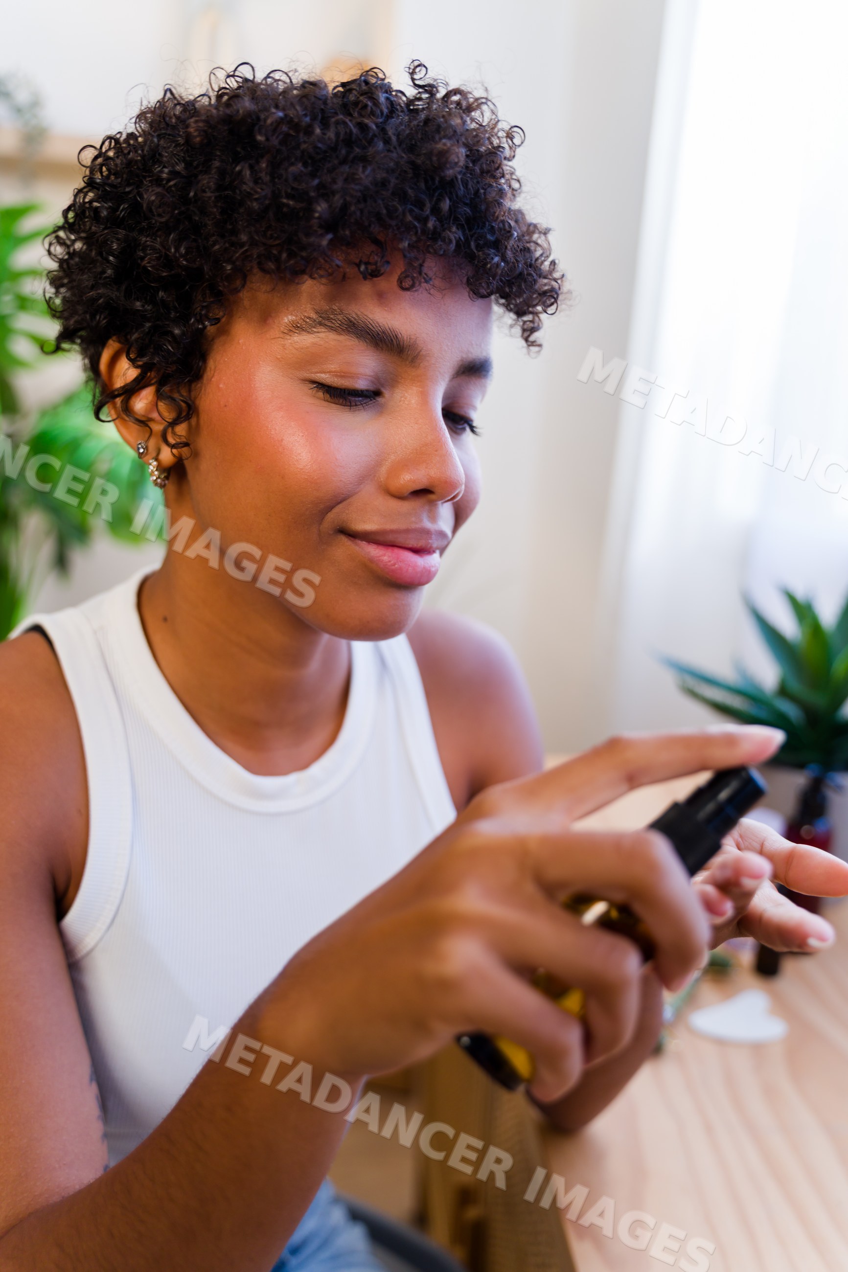 African American woman applying skincare spray on hand indoors