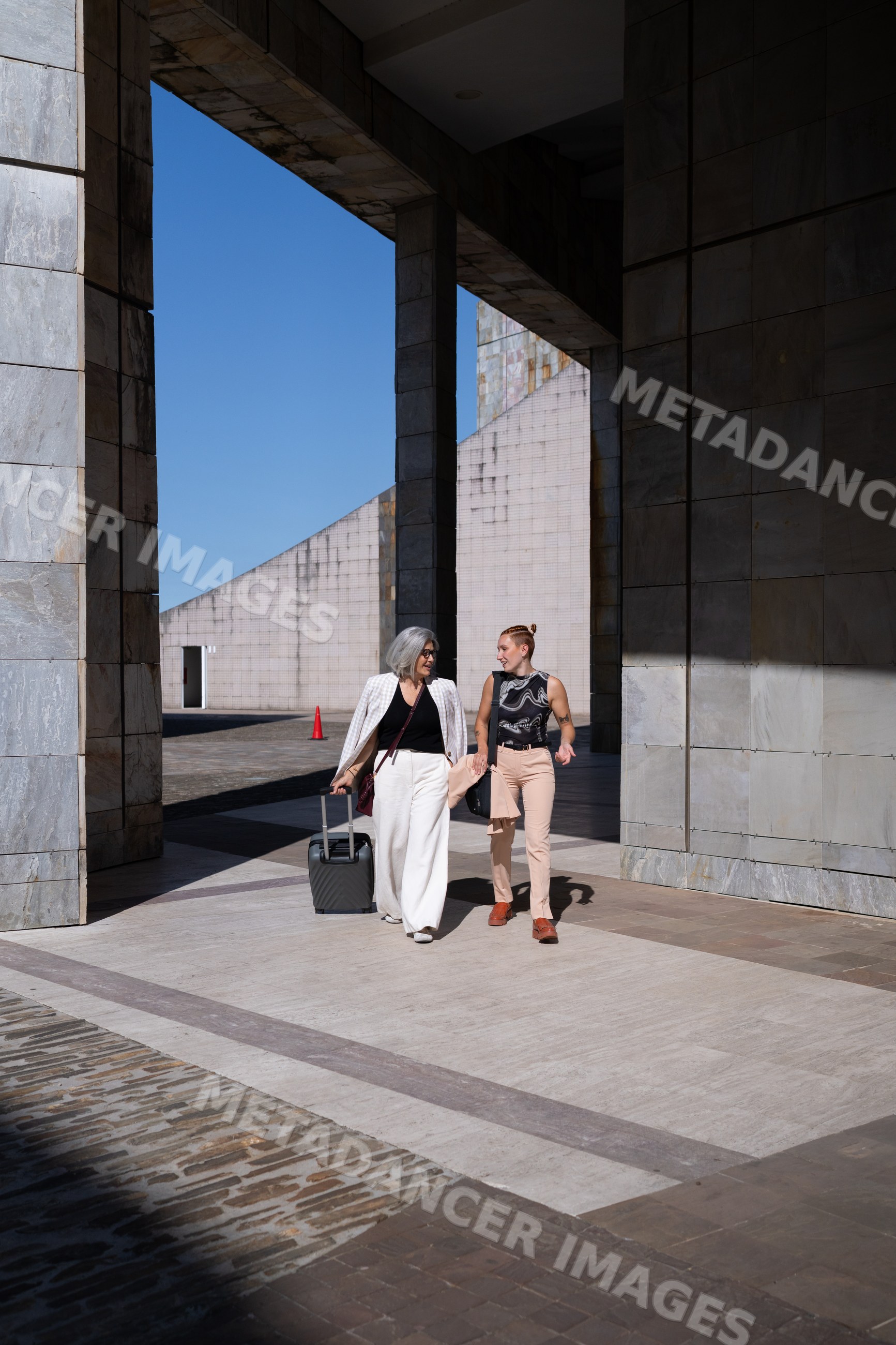 Two businesswomen walking and talking beside modern architecture