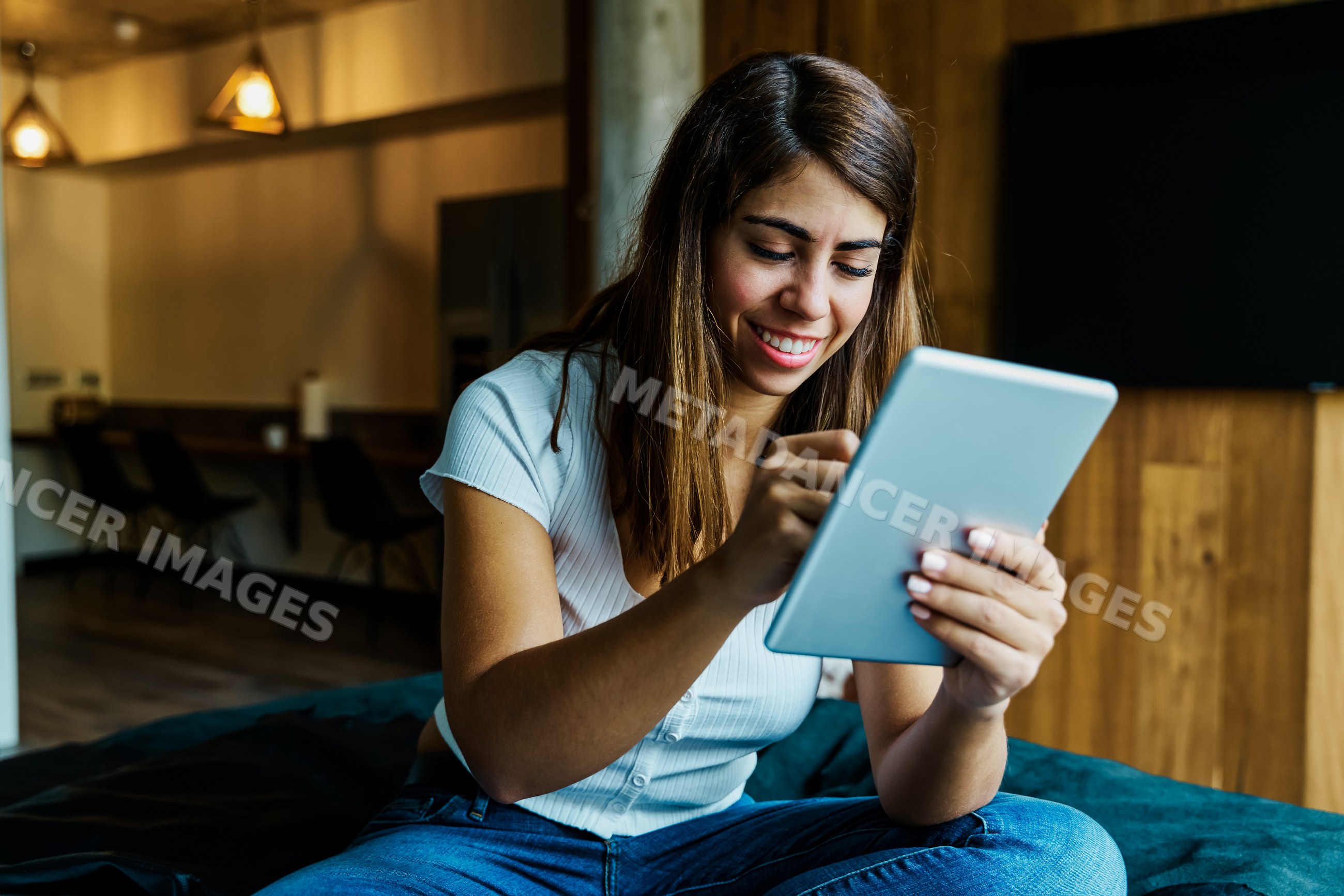 A woman smiling while using a tablet indoors in a cozy Iceland setting