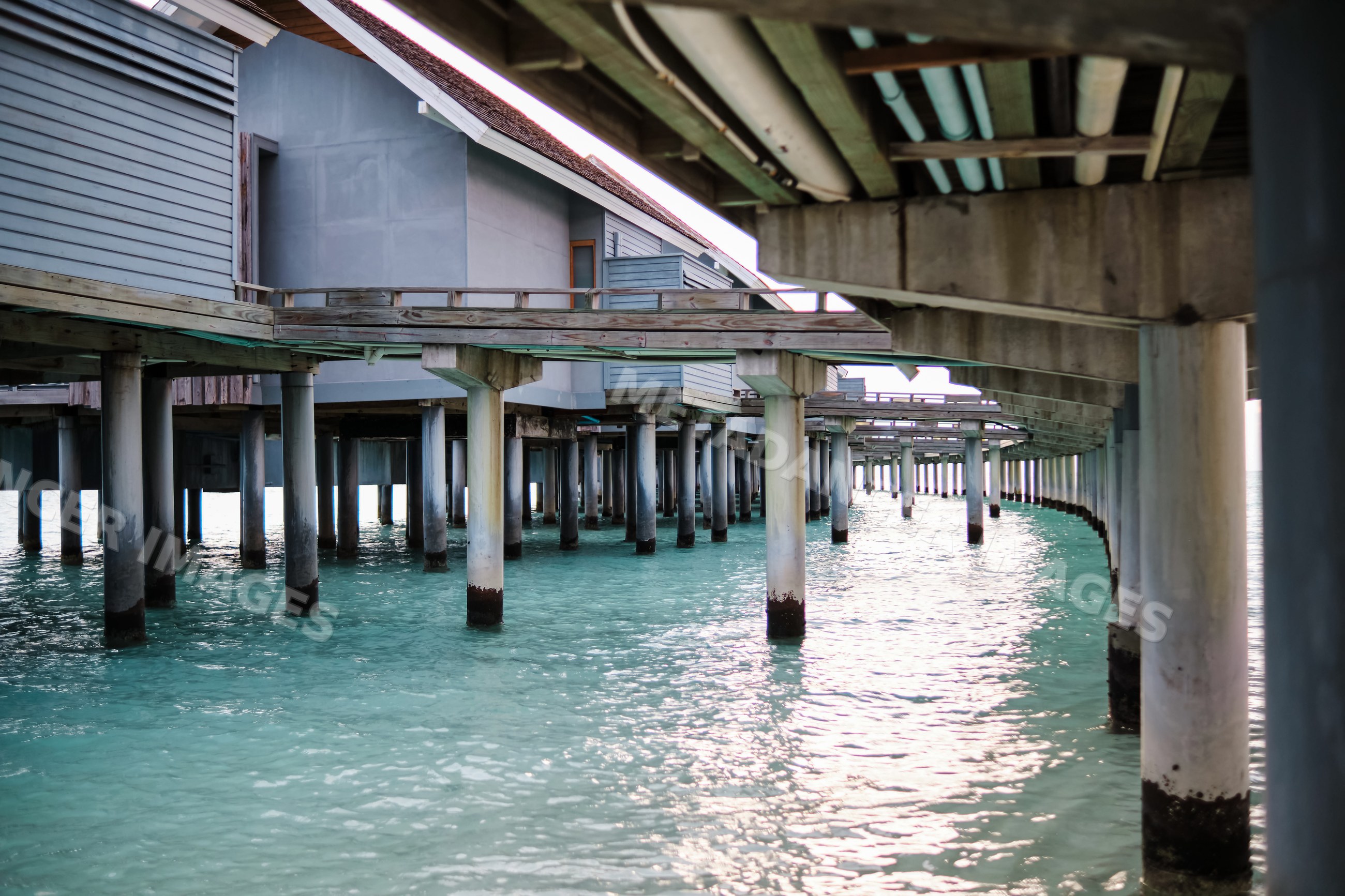 A vacation water villa on stilts above turquoise ocean water