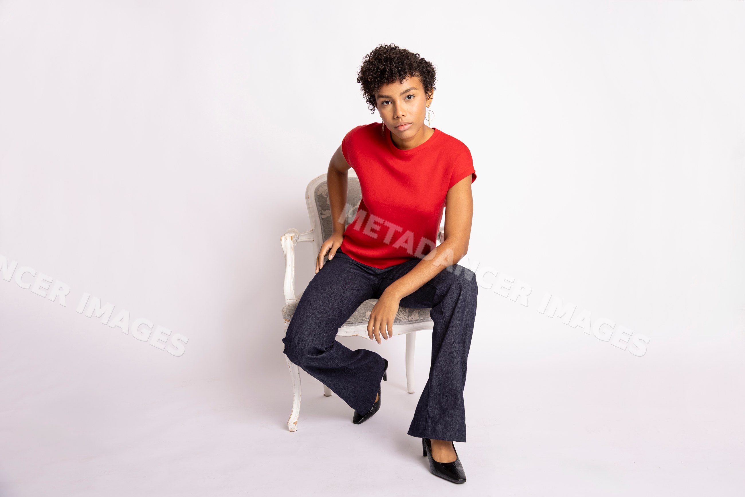 Hispanic woman seated in red shirt and black pants against white