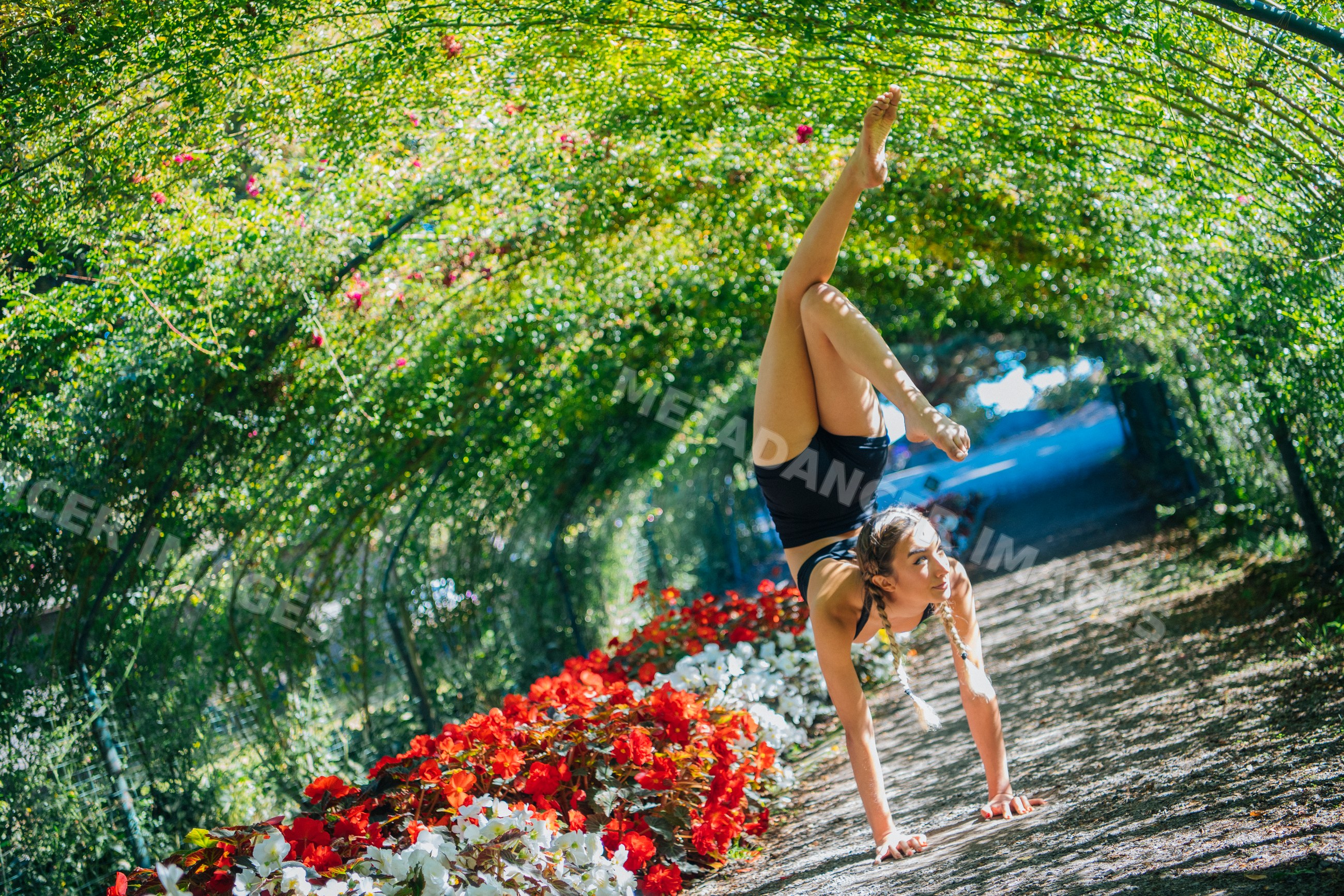White woman performing handstand in a garden tunnel with flowers