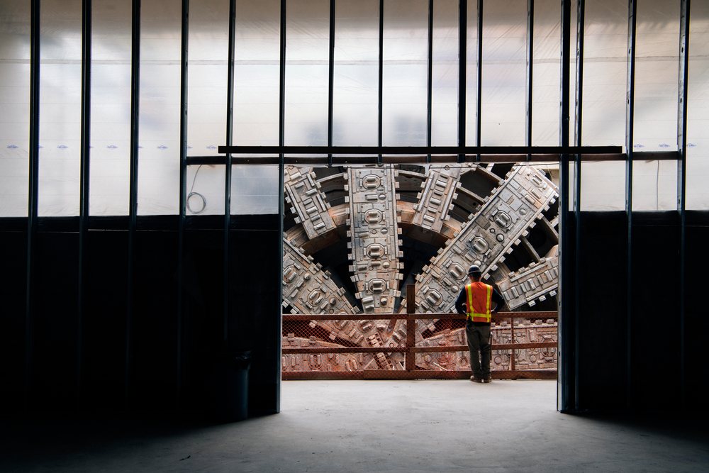 White construction worker inspects a tunnel boring machine