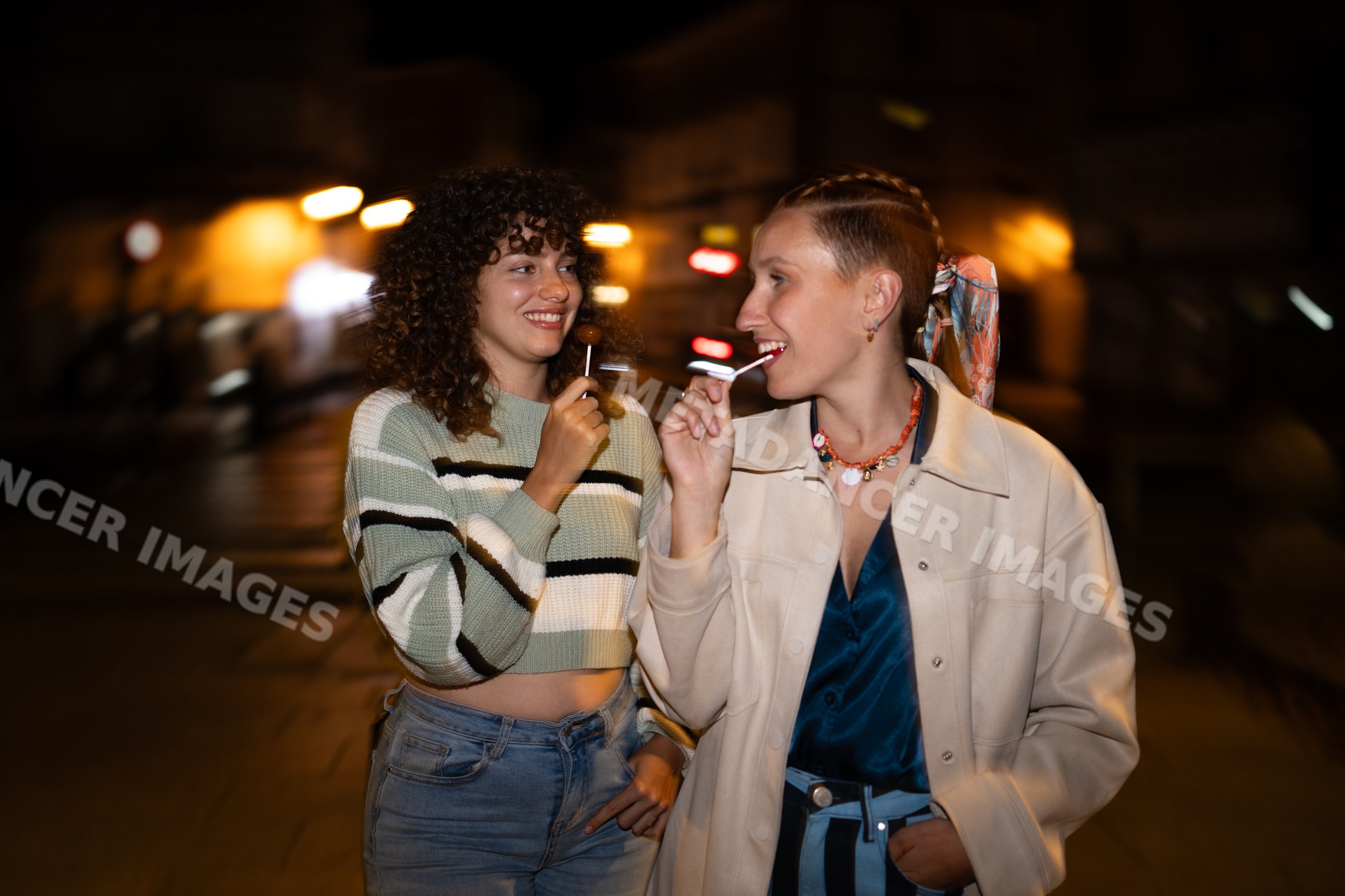 Friends enjoying lollipops on a nighttime street in Santiago