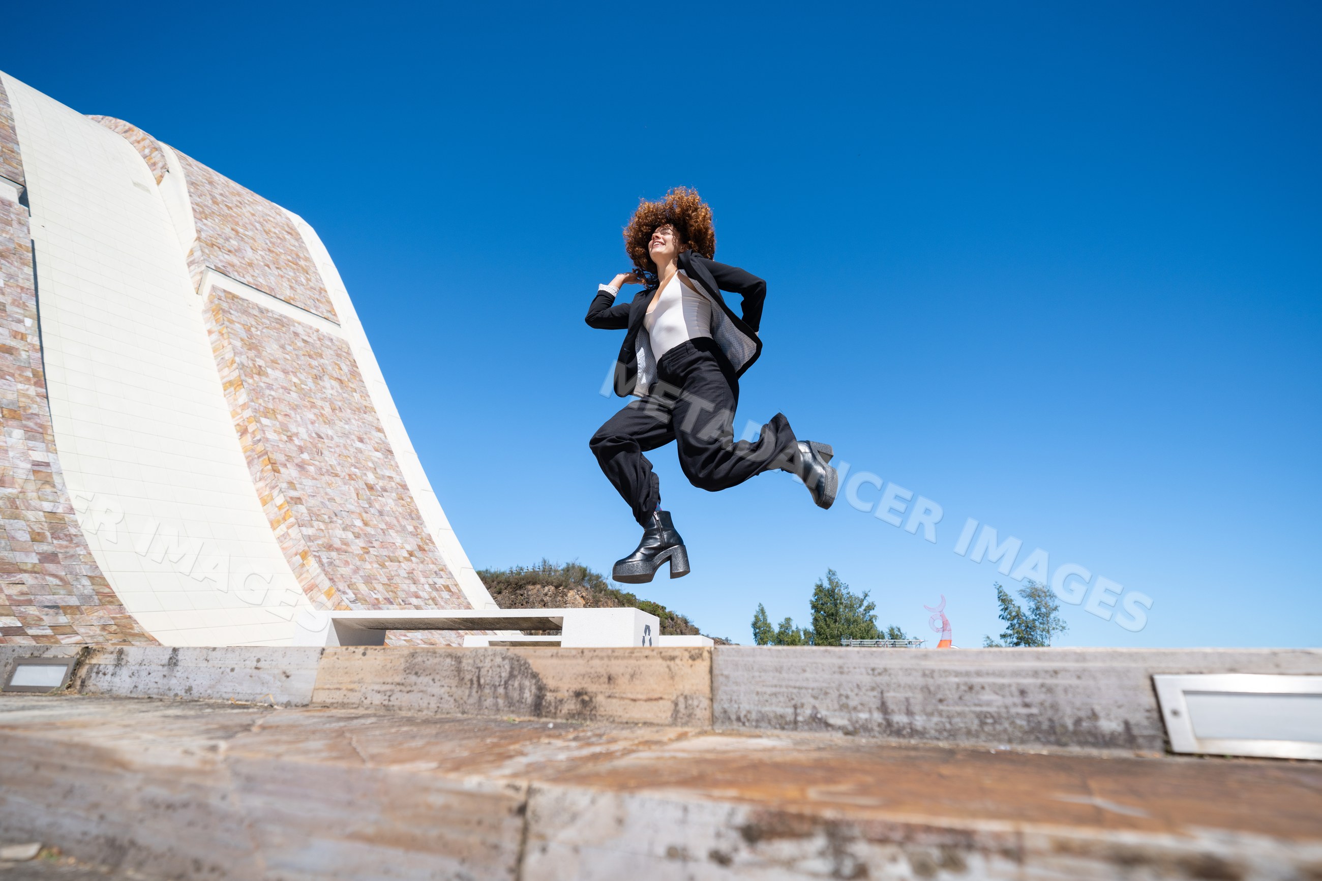 Businesswoman jumping outdoors near a modern building