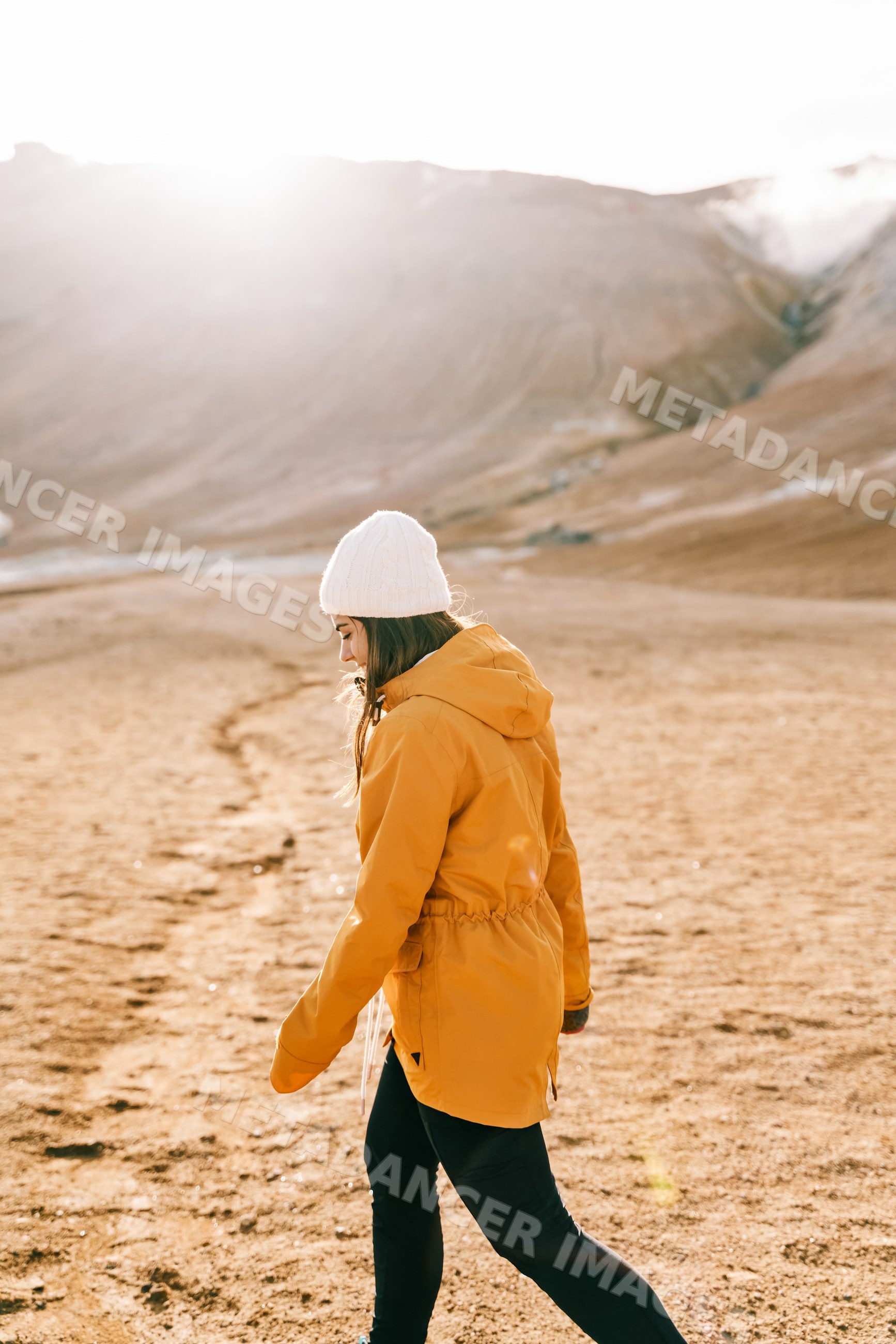 A white woman walks on a mountain trail in Iceland on a sunny day