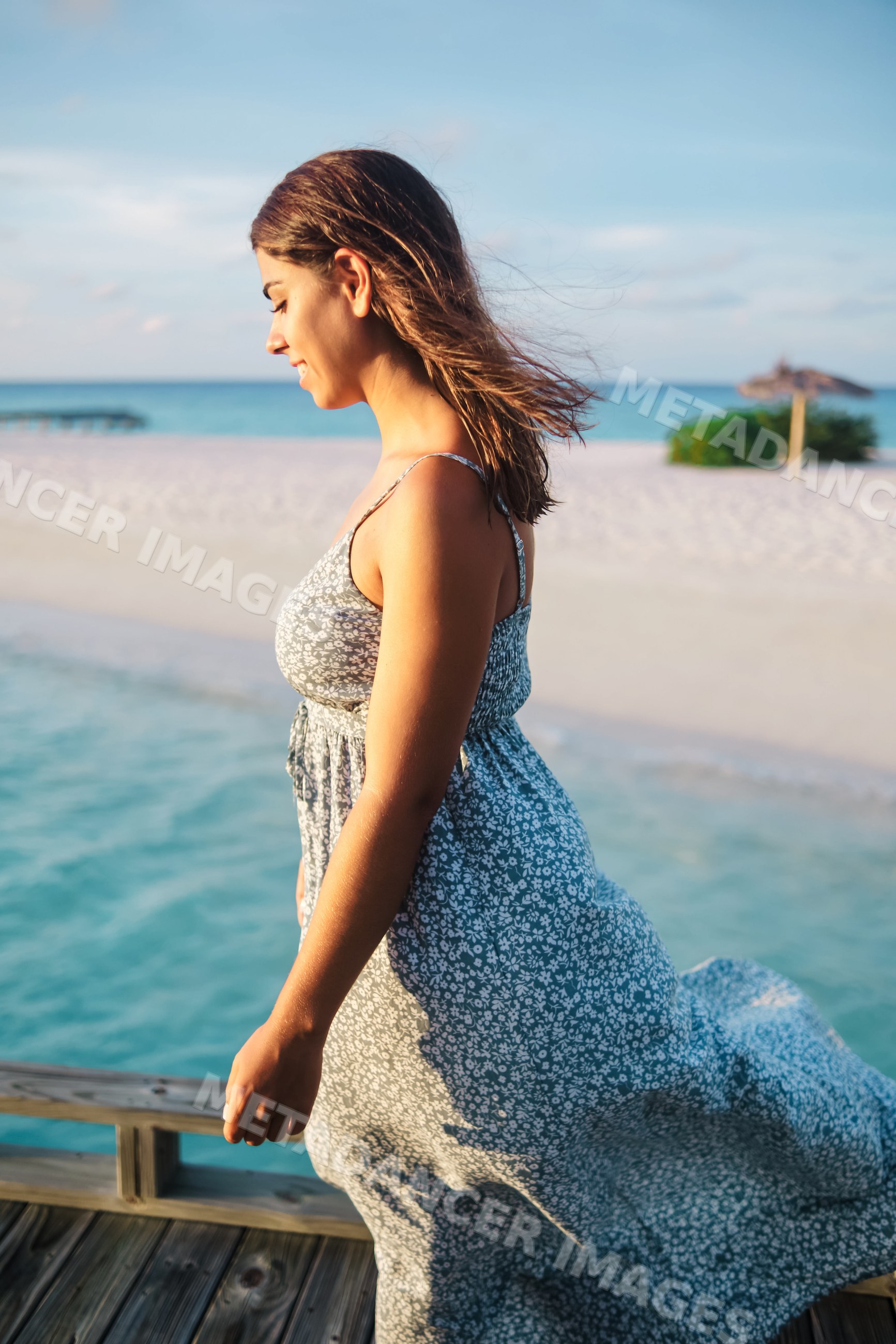 White Woman walking on a boardwalk by a sunny beach in a beach