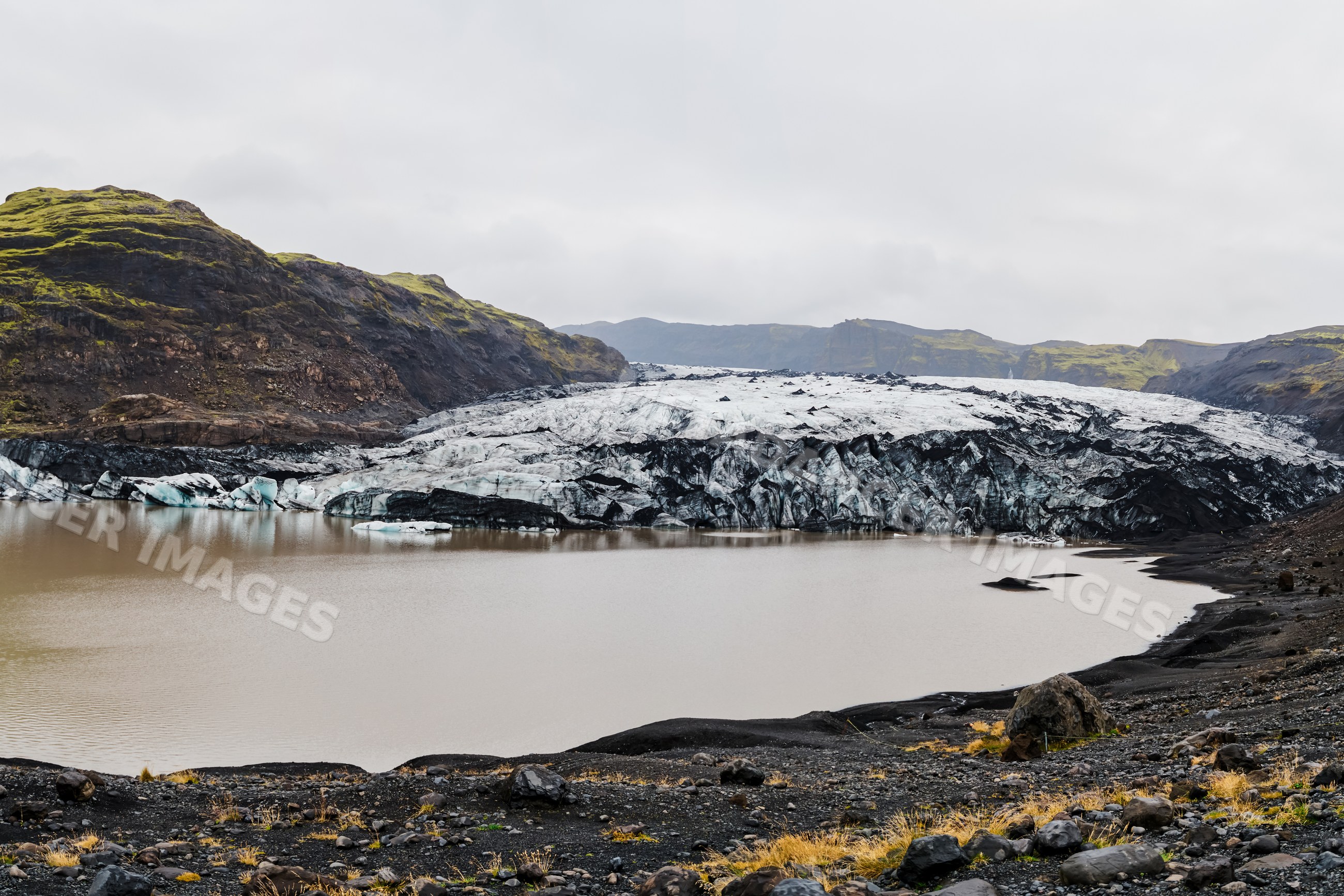 A glacier front melting into a lake amid volcanic terrain