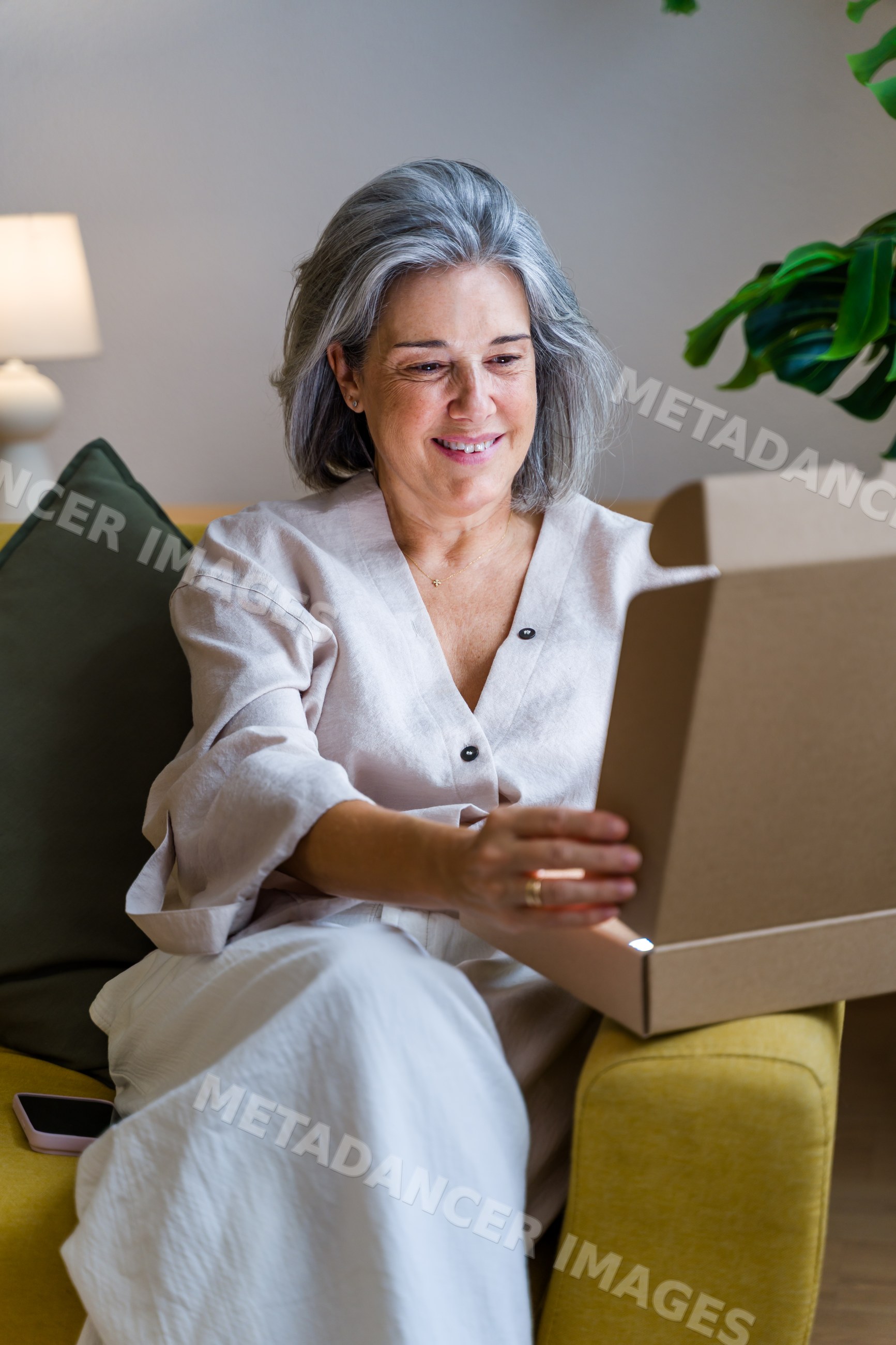 White woman smiling while opening cardboard box indoors