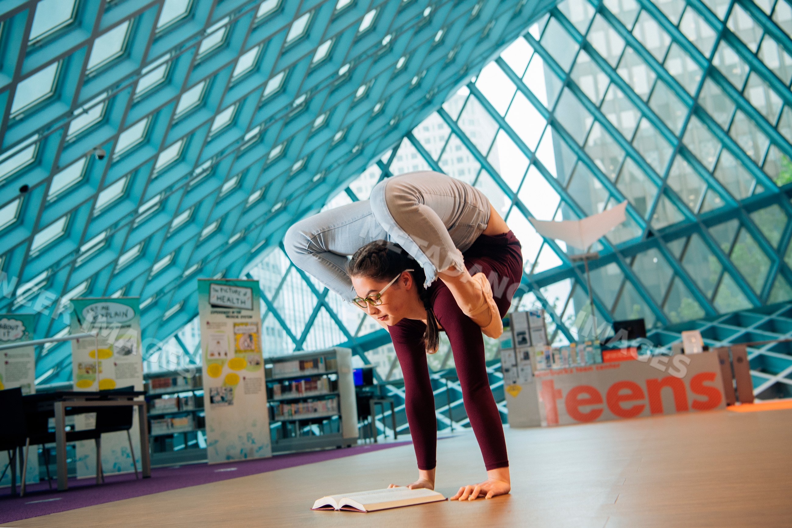 Young woman doing a flexible yoga pose while reading a book