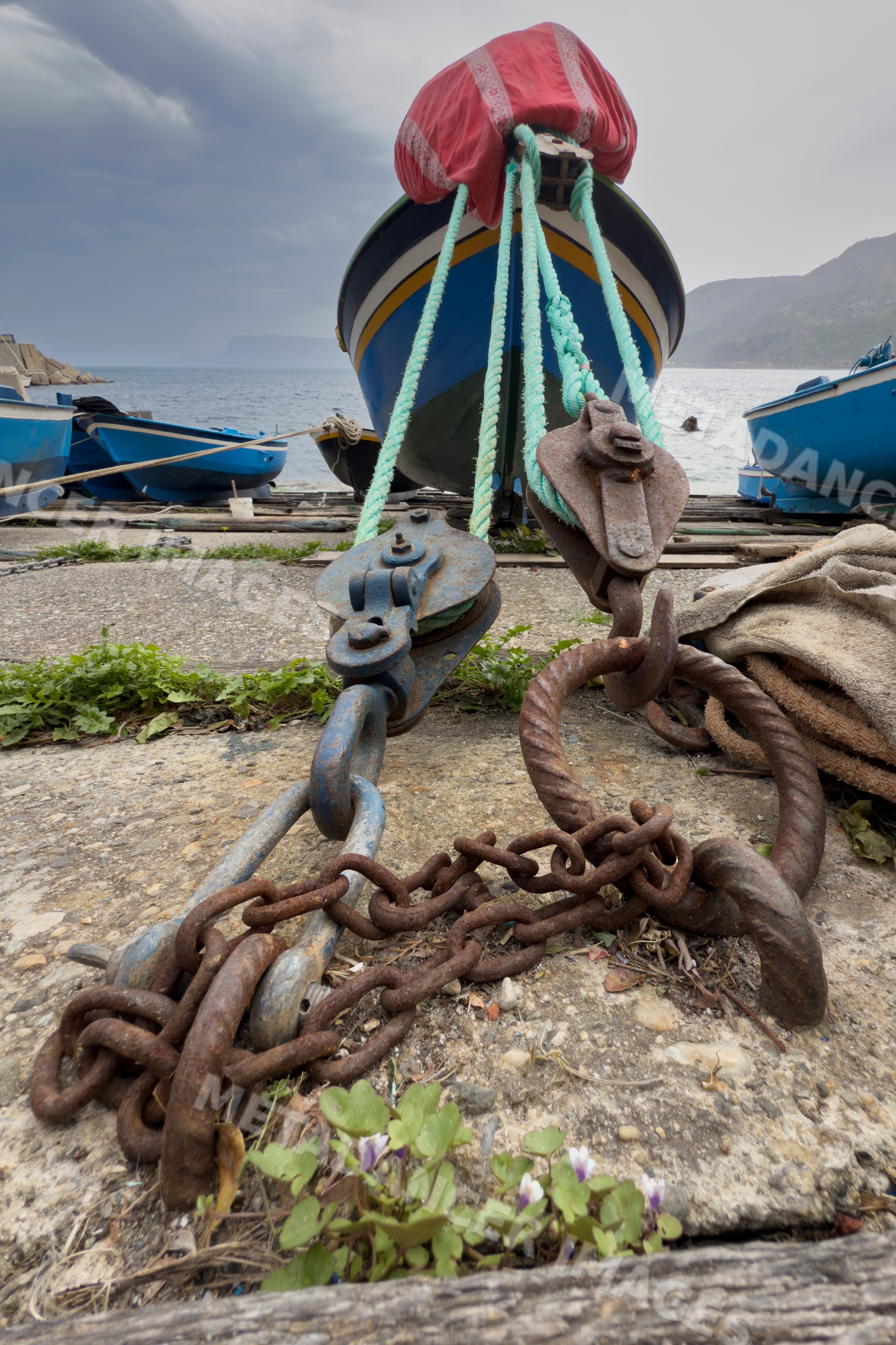 Boat mooring with pulleys and rusty chain in scilla harbour, Italy